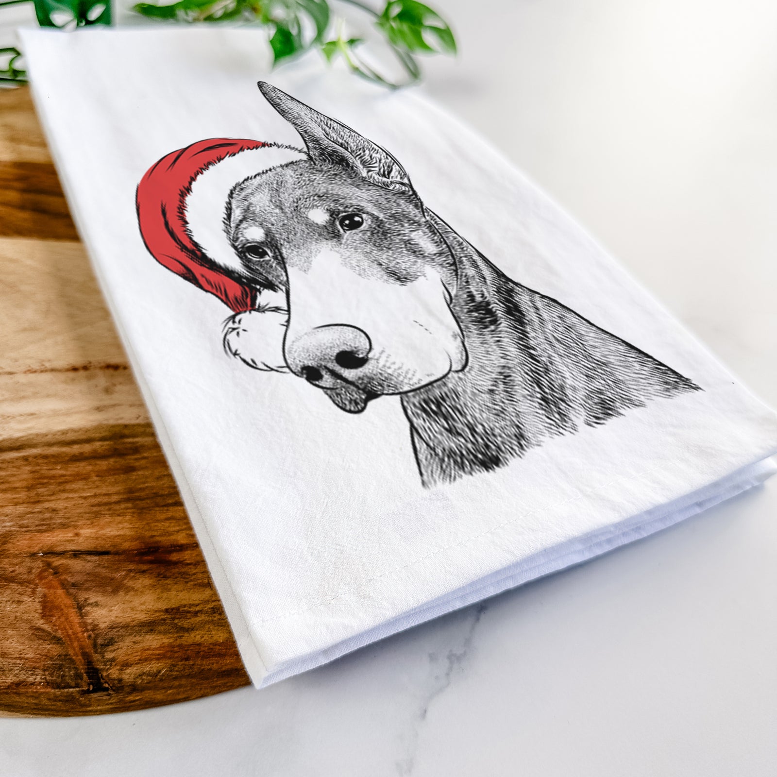 Hand-drawn sketch of Sunny the Doberman Pinscher wearing a Santa hat on a tea towel