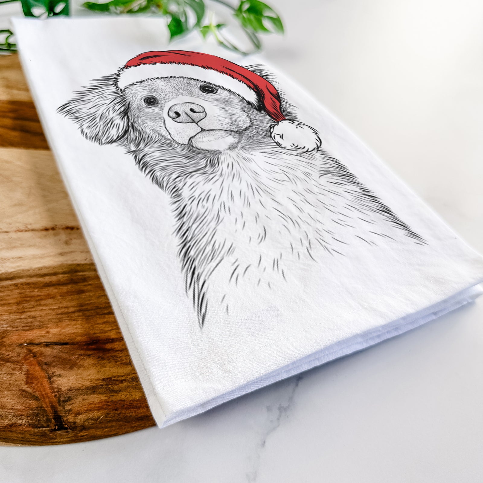Hand-drawn sketch of Vixen the Nova Scotia Duck Tolling Retriever wearing a Santa hat on a tea towel