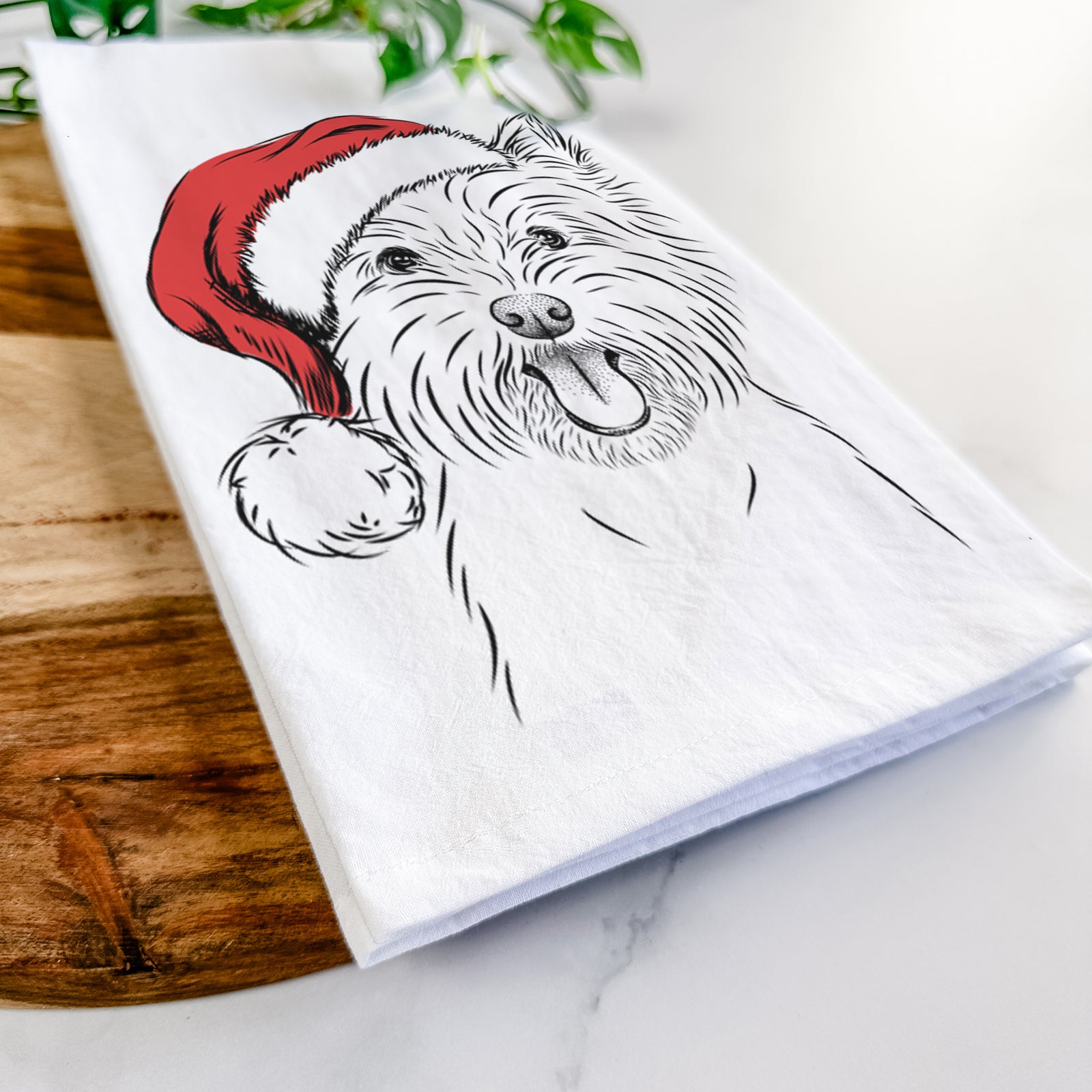 Hand-drawn sketch of Welma the West Highland Terrier wearing a Santa hat on a tea towel