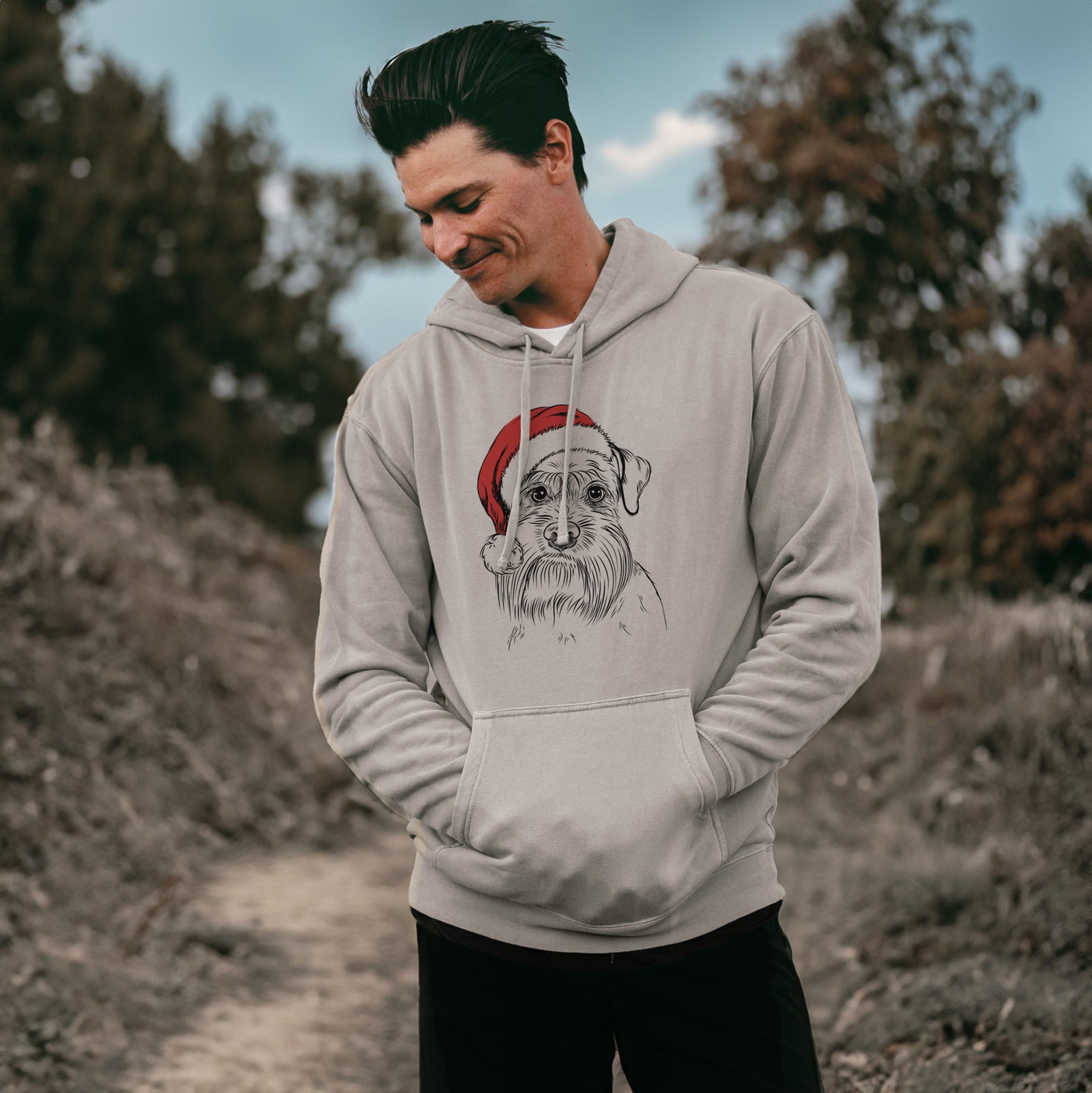 Hand-drawn sketch of Wrigley the Schnauzer wearing a Santa hat on a Cement Unisex pigment dyed hoodie, worn by a man