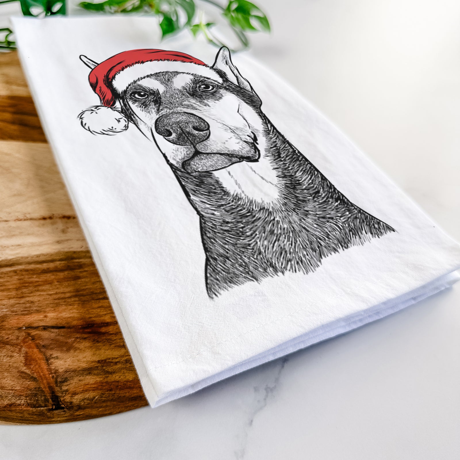 Hand-drawn sketch of Zeus the Doberman Pinscher wearing a Santa hat on a tea towel