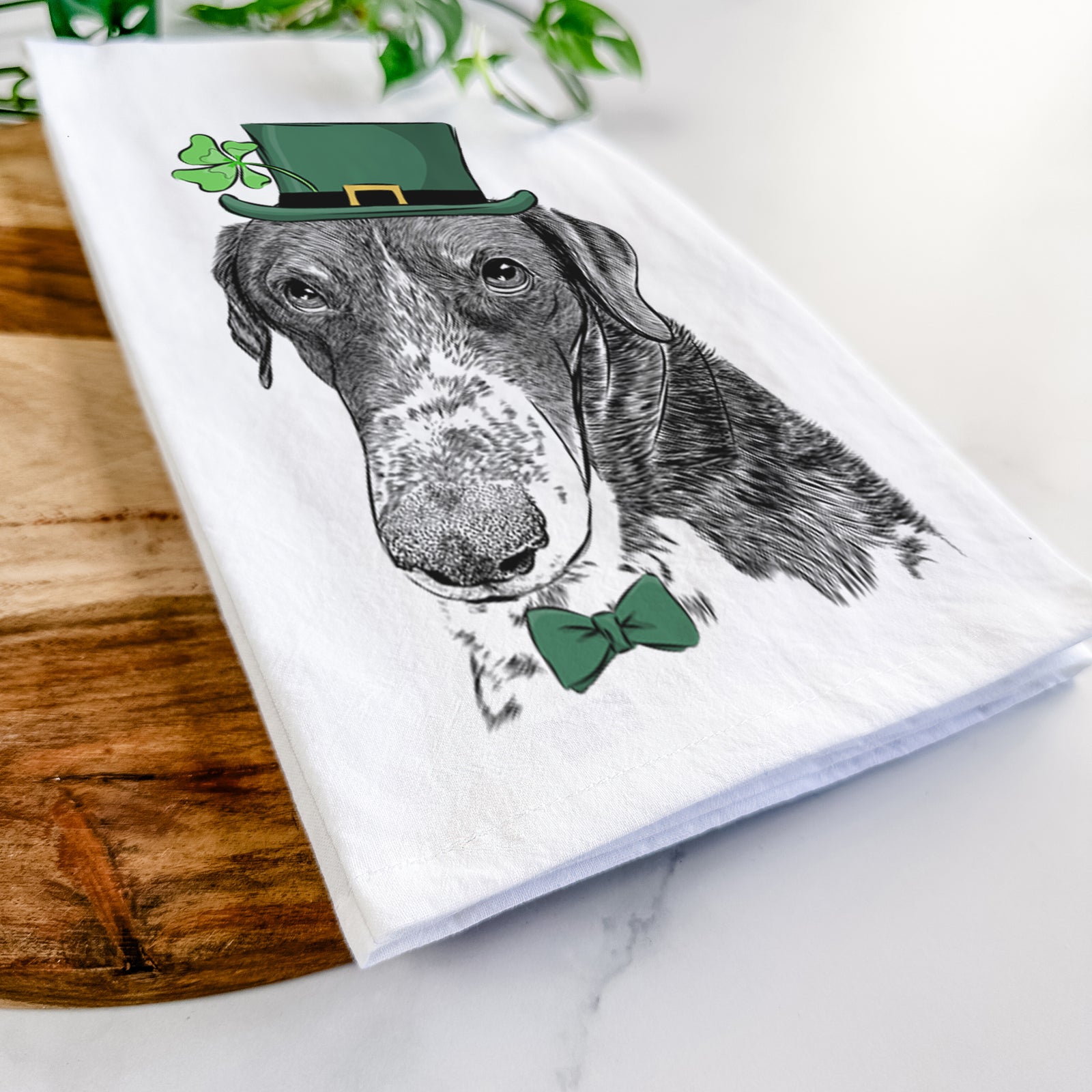 Hand-drawn sketch of Angel Orion the Mixed Breed wearing a St. Patrick's Day leprechaun hat and bow tie on a tea towel