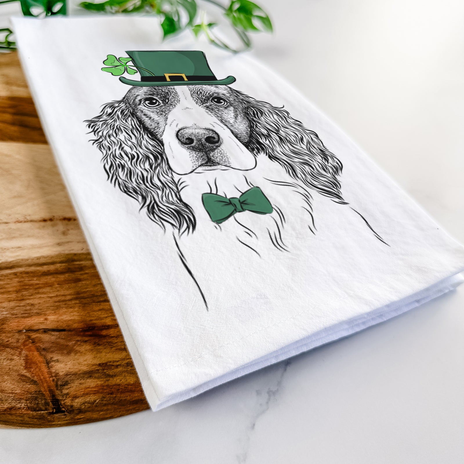 Hand-drawn sketch of Annie the English Springer Spaniel wearing a St. Patrick's Day leprechaun hat and bow tie on a tea towel