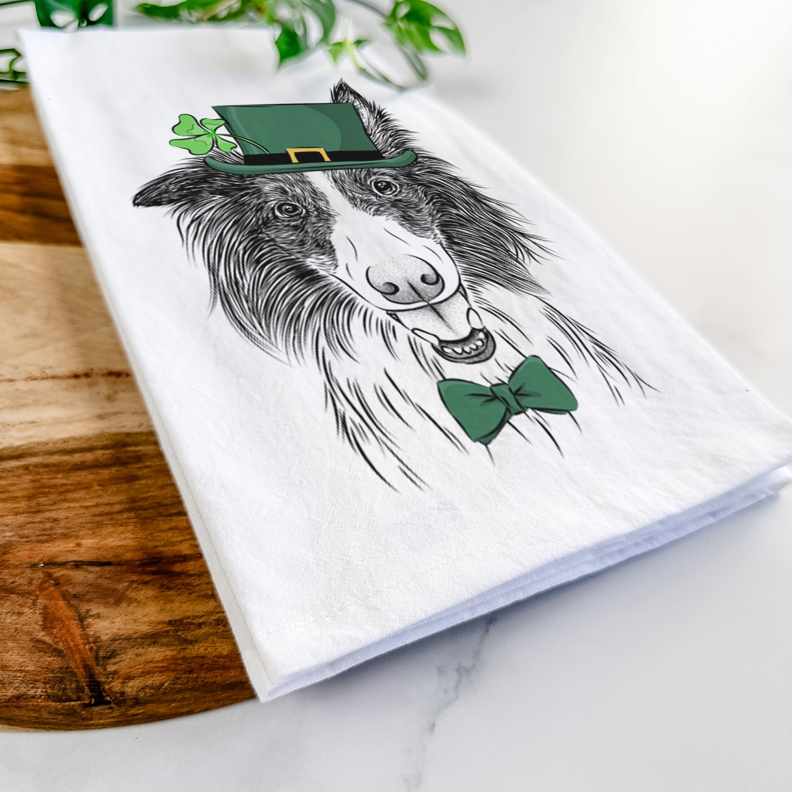 Hand-drawn sketch of Archie the Silken Windhound wearing a St. Patrick's Day leprechaun hat and bow tie on a tea towel