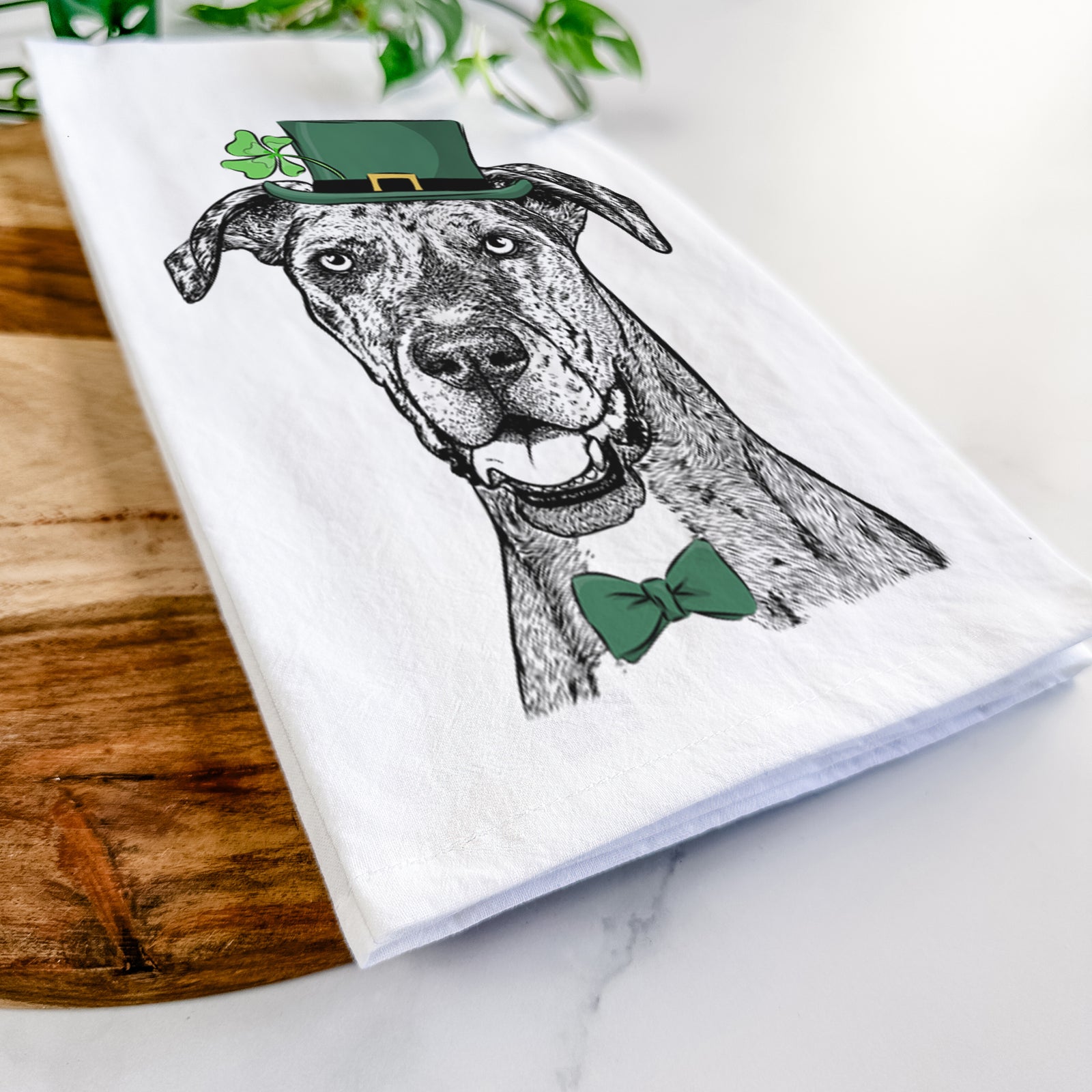 Hand-drawn sketch of Athena the Merle Great Dane wearing a St. Patrick's Day leprechaun hat and bow tie on a tea towel