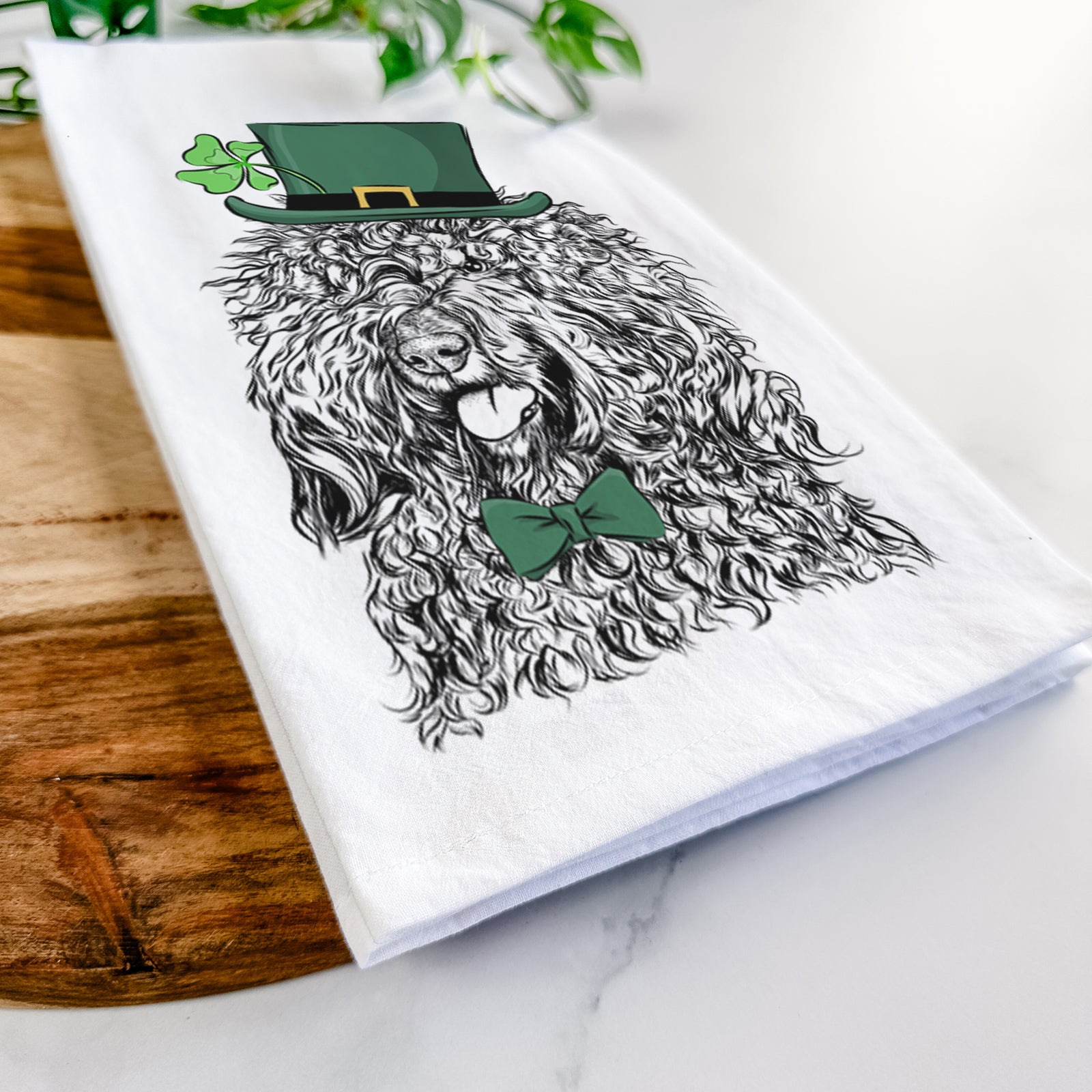 Hand-drawn sketch of Babs the Barbet wearing a St. Patrick's Day leprechaun hat and bow tie on a tea towel