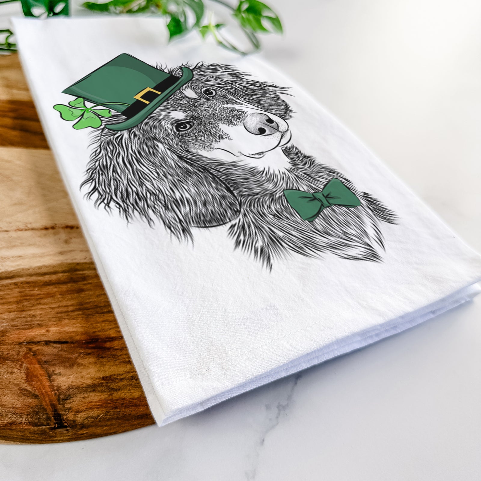 Hand-drawn sketch of Bailey the Long Haired Dachshund wearing a St. Patrick's Day leprechaun hat and bow tie on a tea towel
