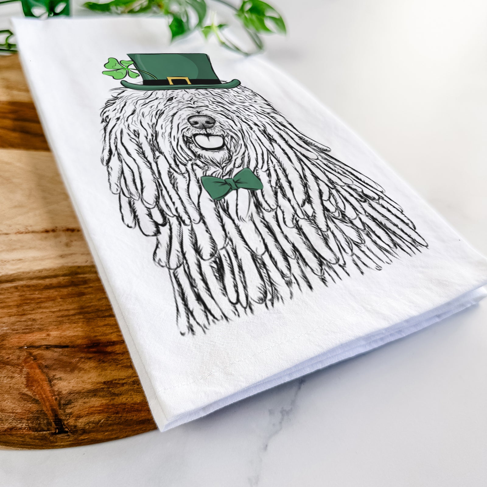 Hand-drawn sketch of Barry the Komondor wearing a St. Patrick's Day leprechaun hat and bow tie on a tea towel