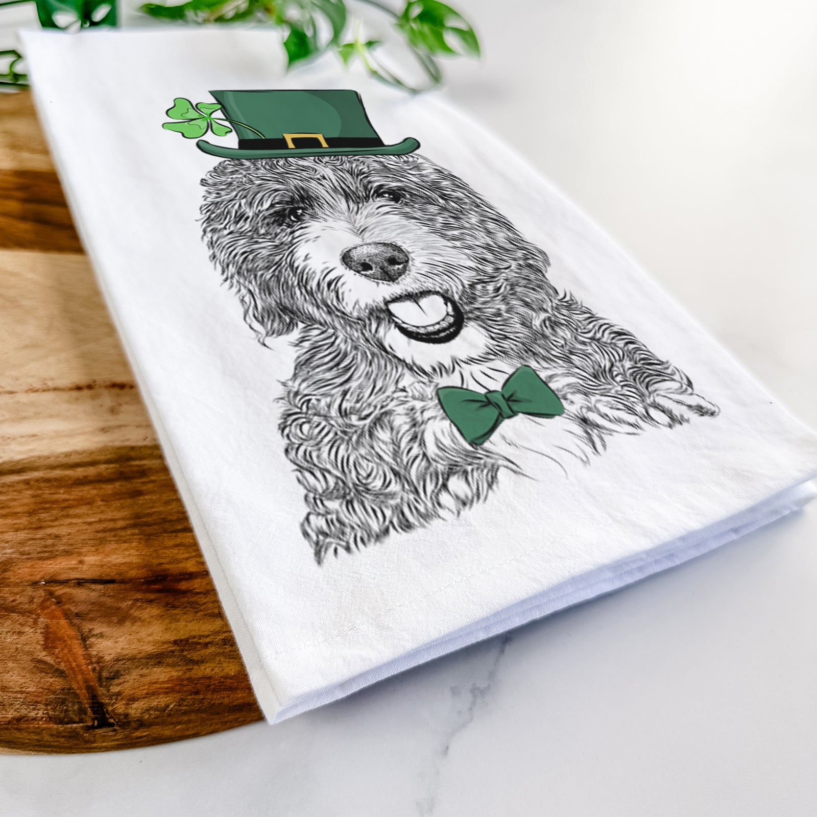 Hand-drawn sketch of Bash the Bernedoodle wearing a St. Patrick's Day leprechaun hat and bow tie on a tea towel