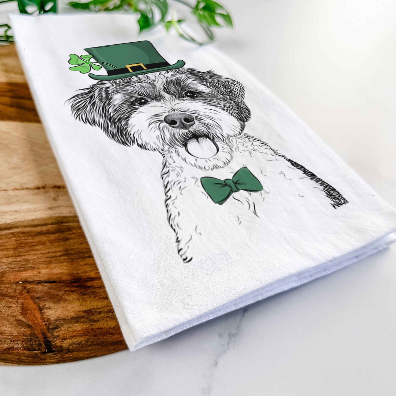 Hand-drawn sketch of Bella the Cockapoo wearing a St. Patrick's Day leprechaun hat and bow tie on a tea towel