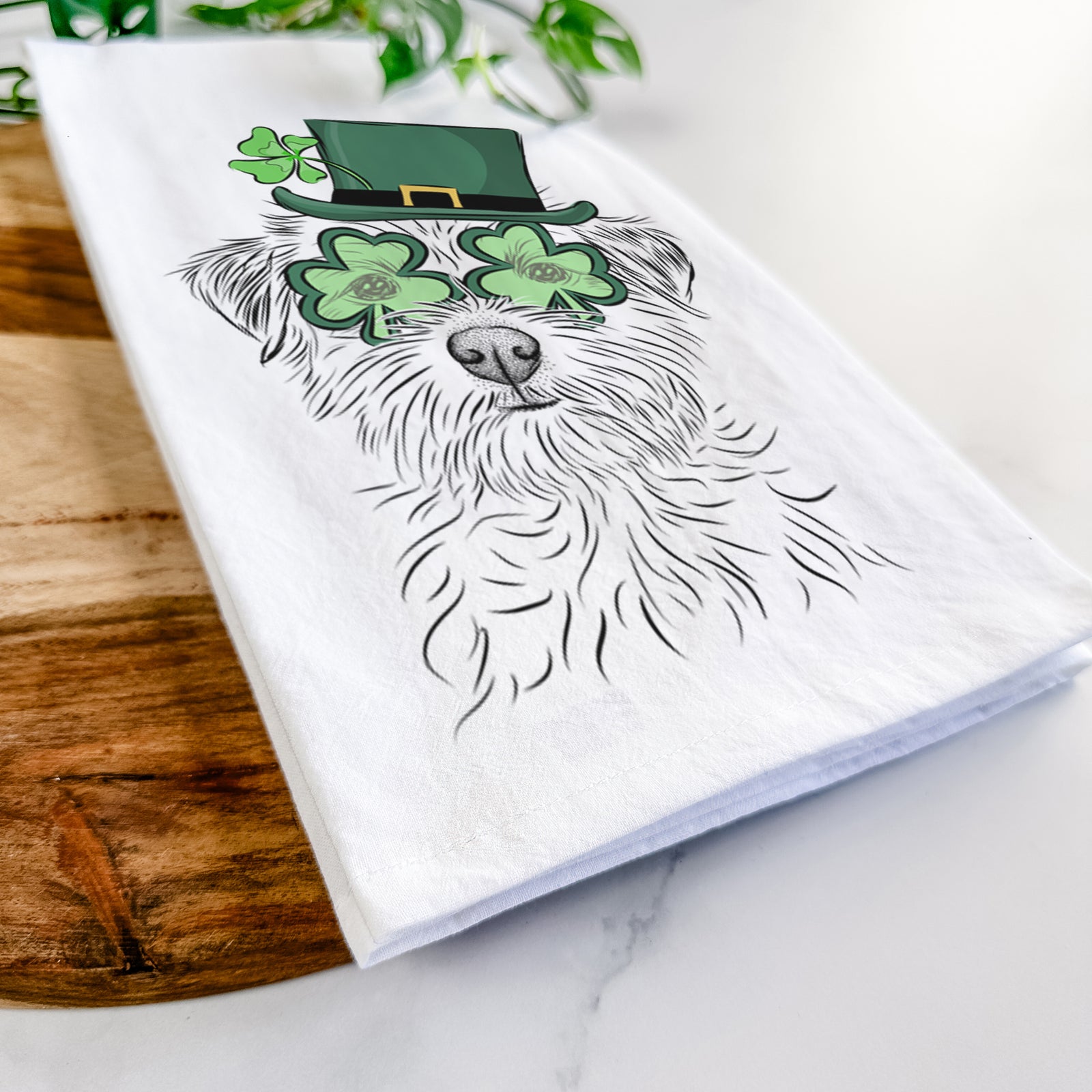 Hand-drawn sketch of Benjamin the Border Terrier wearing a St. Patrick's Day leprechaun hat and bow tie on a tea towel