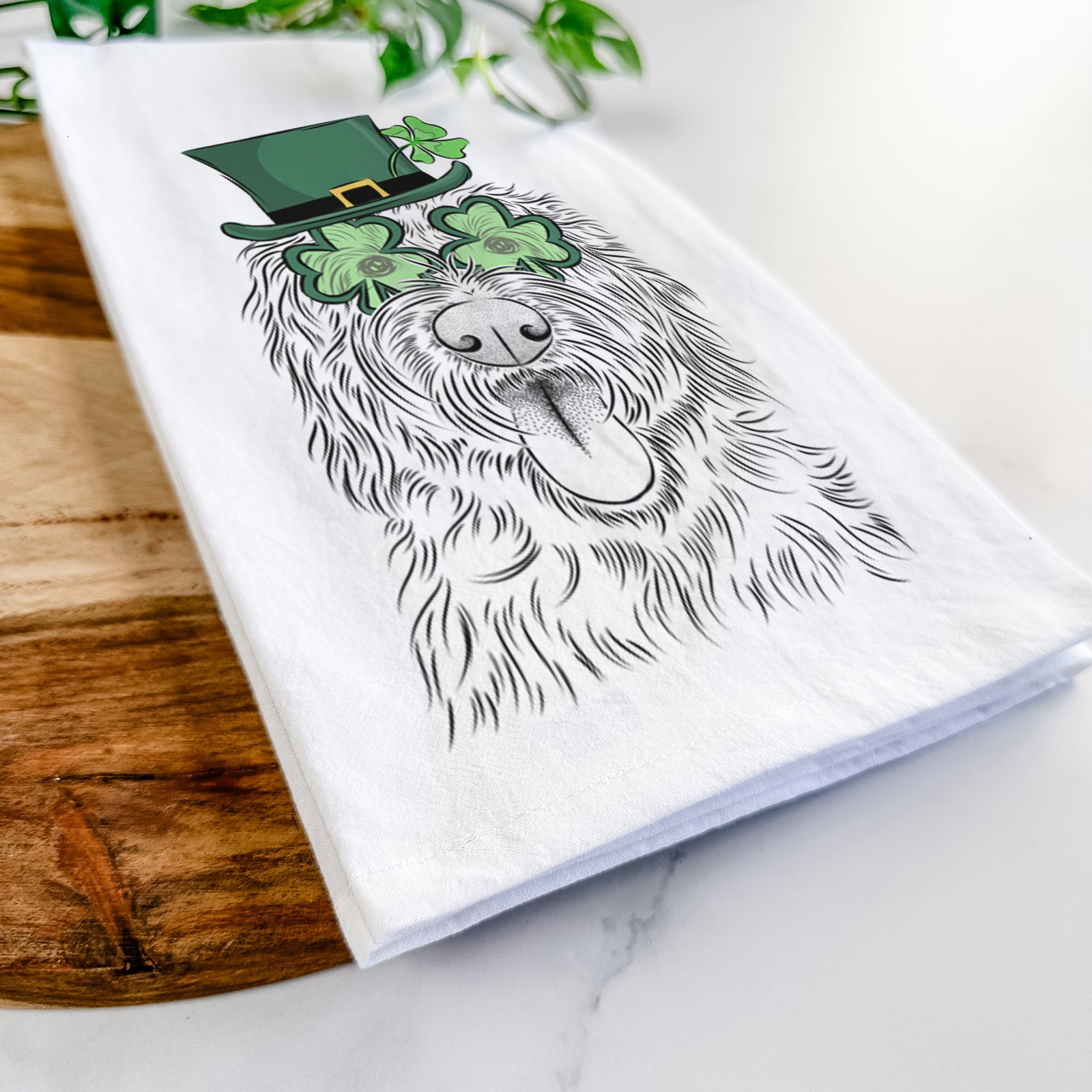 Hand-drawn sketch of Bennett the Doodle wearing a St. Patrick's Day leprechaun hat and bow tie on a tea towel