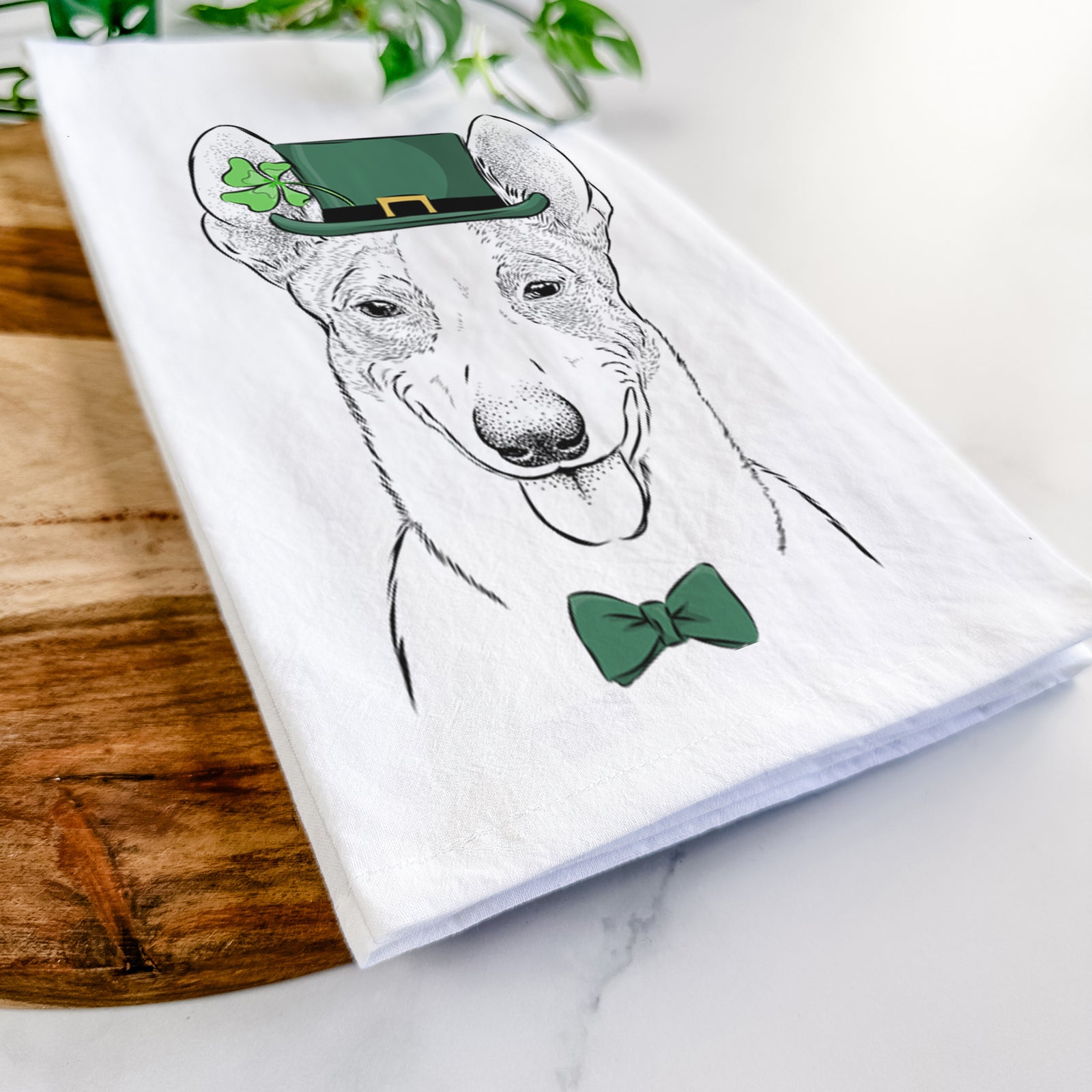 Hand-drawn sketch of Berlin the Carolina Dog wearing a St. Patrick's Day leprechaun hat and bow tie on a tea towel