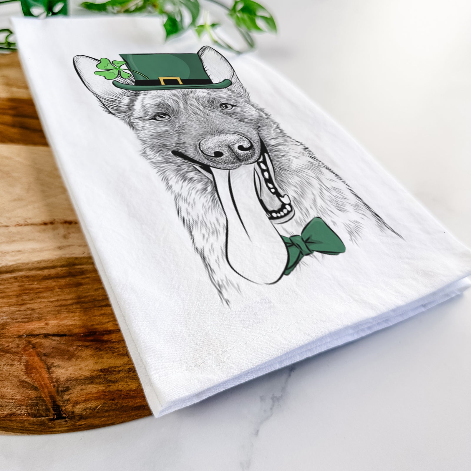Hand-drawn sketch of Bessa the Dutch Shepherd wearing a St. Patrick's Day leprechaun hat and bow tie on a tea towel