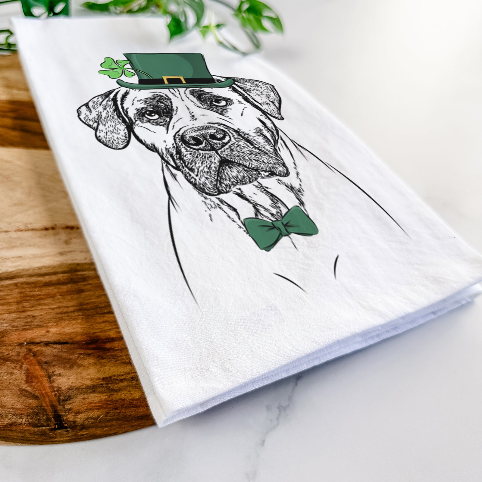 Hand-drawn sketch of Boris the Boerboel wearing a St. Patrick's Day leprechaun hat and bow tie on a tea towel