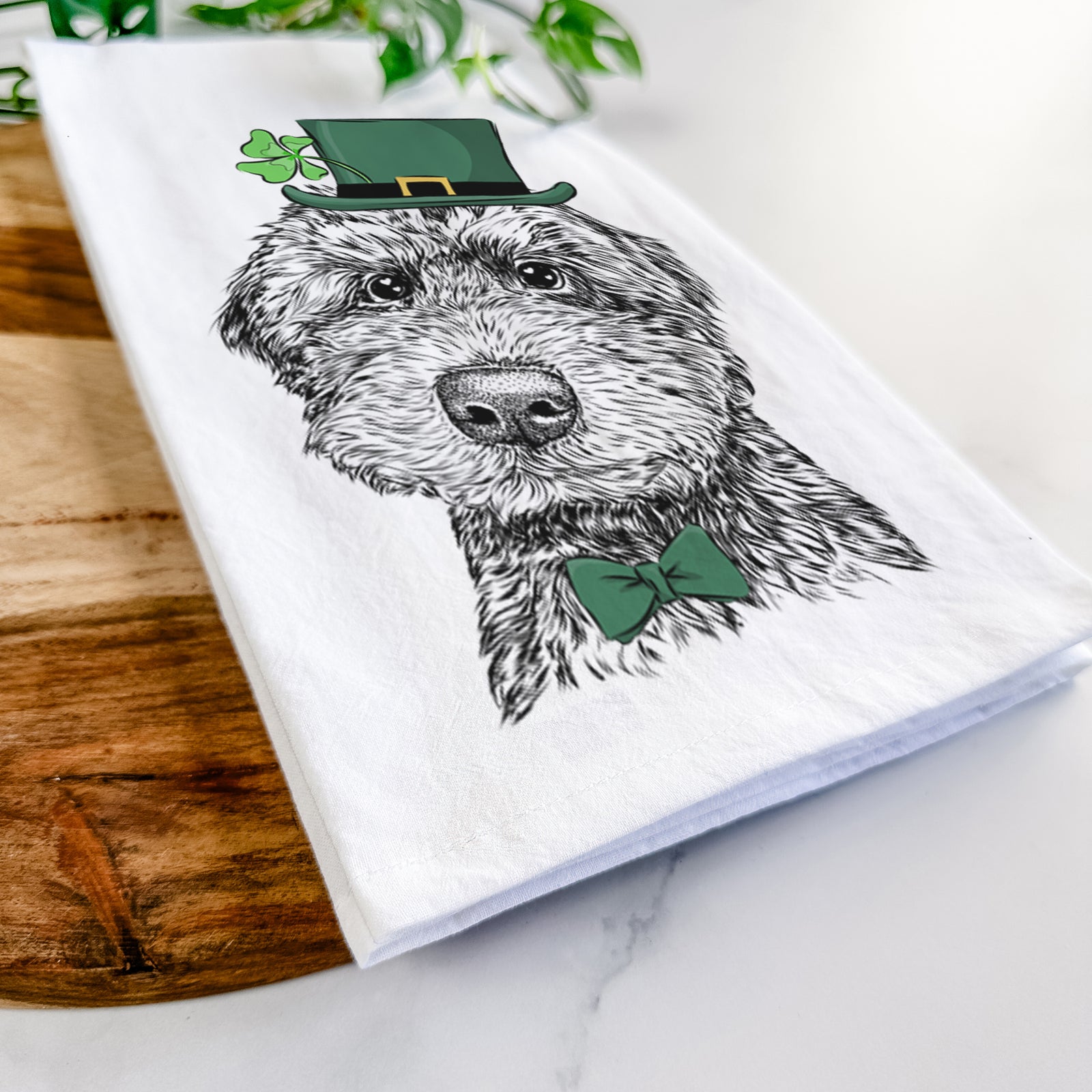 Hand-drawn sketch of Bowser the Whoodle wearing a St. Patrick's Day leprechaun hat and bow tie on a tea towel