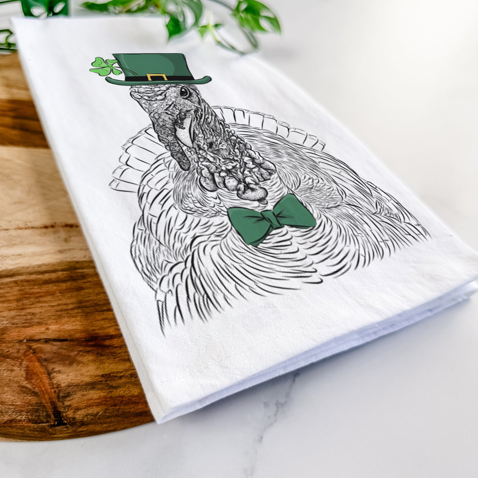Hand-drawn sketch of Brady the Turkey wearing a St. Patrick's Day leprechaun hat and bow tie on a tea towel