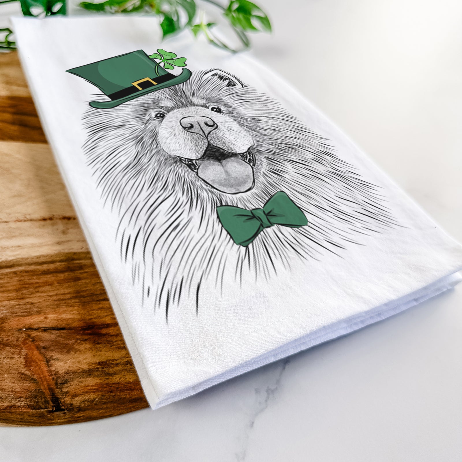 Hand-drawn sketch of Charming Charlie the Chow Chow wearing a St. Patrick's Day leprechaun hat and bow tie on a tea towel