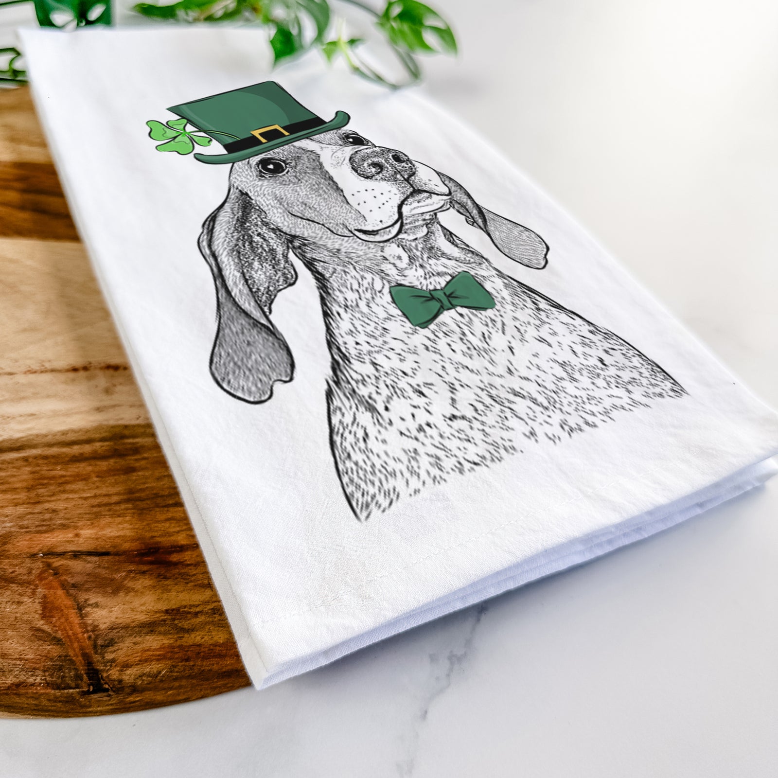 Hand-drawn sketch of Chester the Red Tick Coonhound wearing a St. Patrick's Day leprechaun hat and bow tie on a tea towel