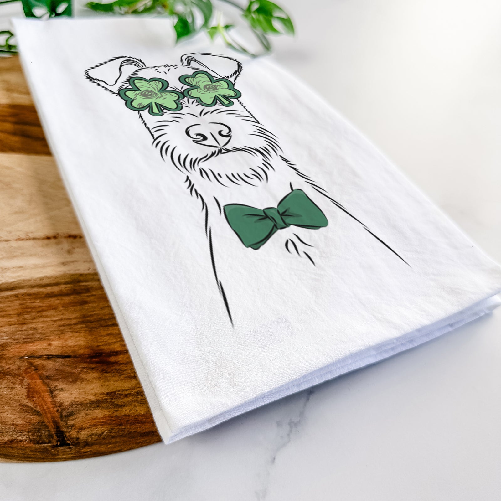 Hand-drawn sketch of Connor the Irish Terrier wearing a St. Patrick's Day leprechaun hat and bow tie on a tea towel