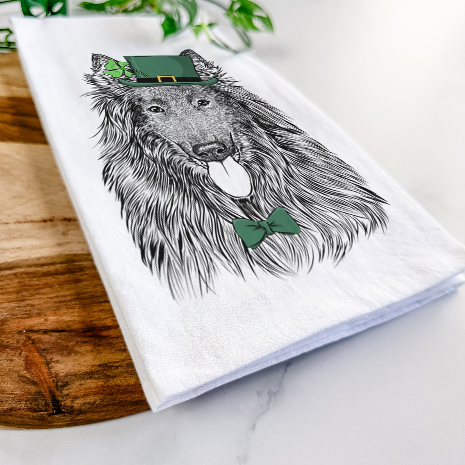 Hand-drawn sketch of Daan the Belgian Shepherd wearing a St. Patrick's Day leprechaun hat and bow tie on a tea towel