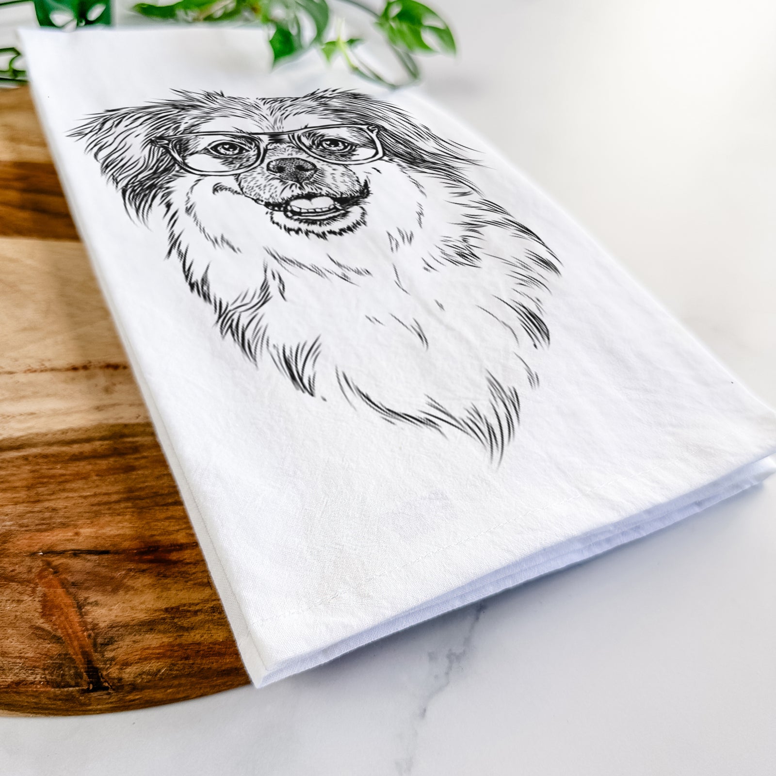 Hand-drawn sketch of Ed the Tibetan Spaniel wearing a St. Patrick's Day leprechaun hat and bow tie on a tea towel
