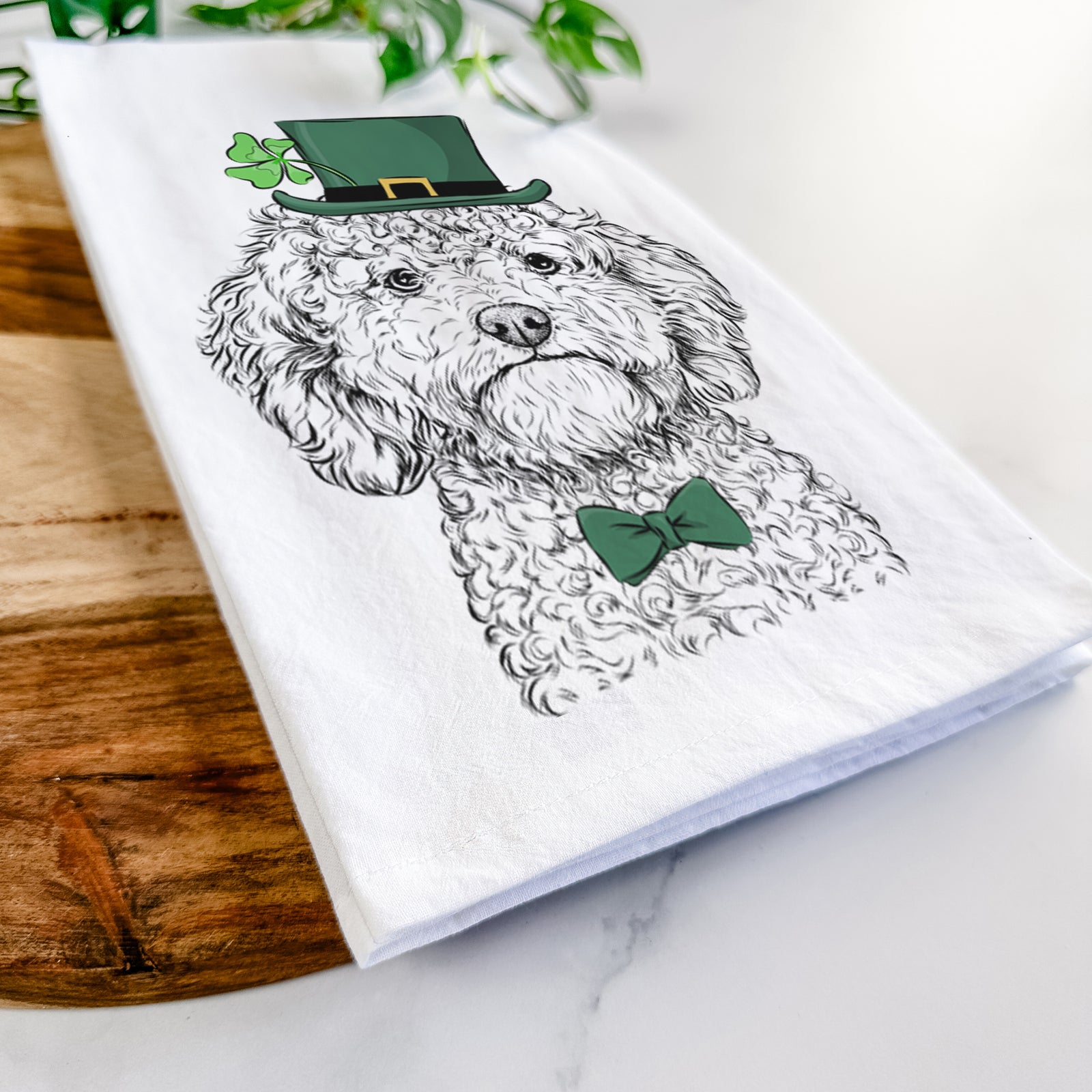 Hand-drawn sketch of Edgar the Shihpoo wearing a St. Patrick's Day leprechaun hat and bow tie on a tea towel