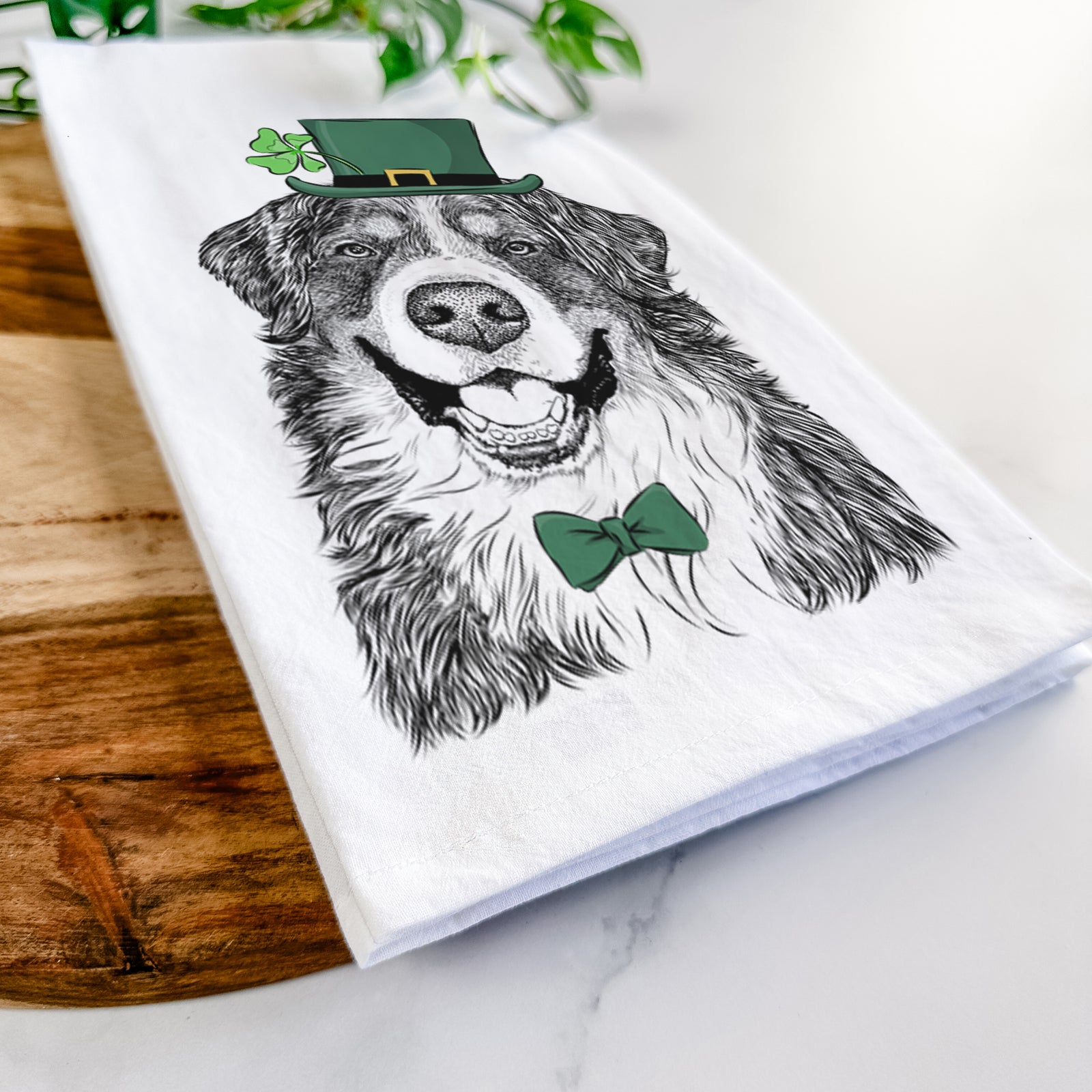 Hand-drawn sketch of Eiger the Bernese Mountain Dog wearing a St. Patrick's Day leprechaun hat and bow tie on a tea towel