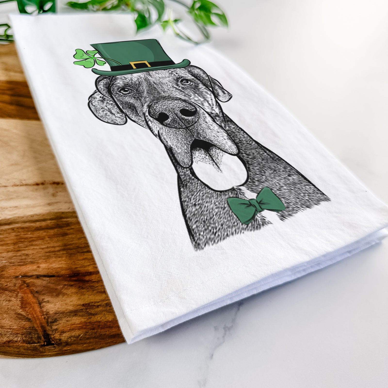 Hand-drawn sketch of Eli the Great Dane wearing a St. Patrick's Day leprechaun hat and bow tie on a tea towel