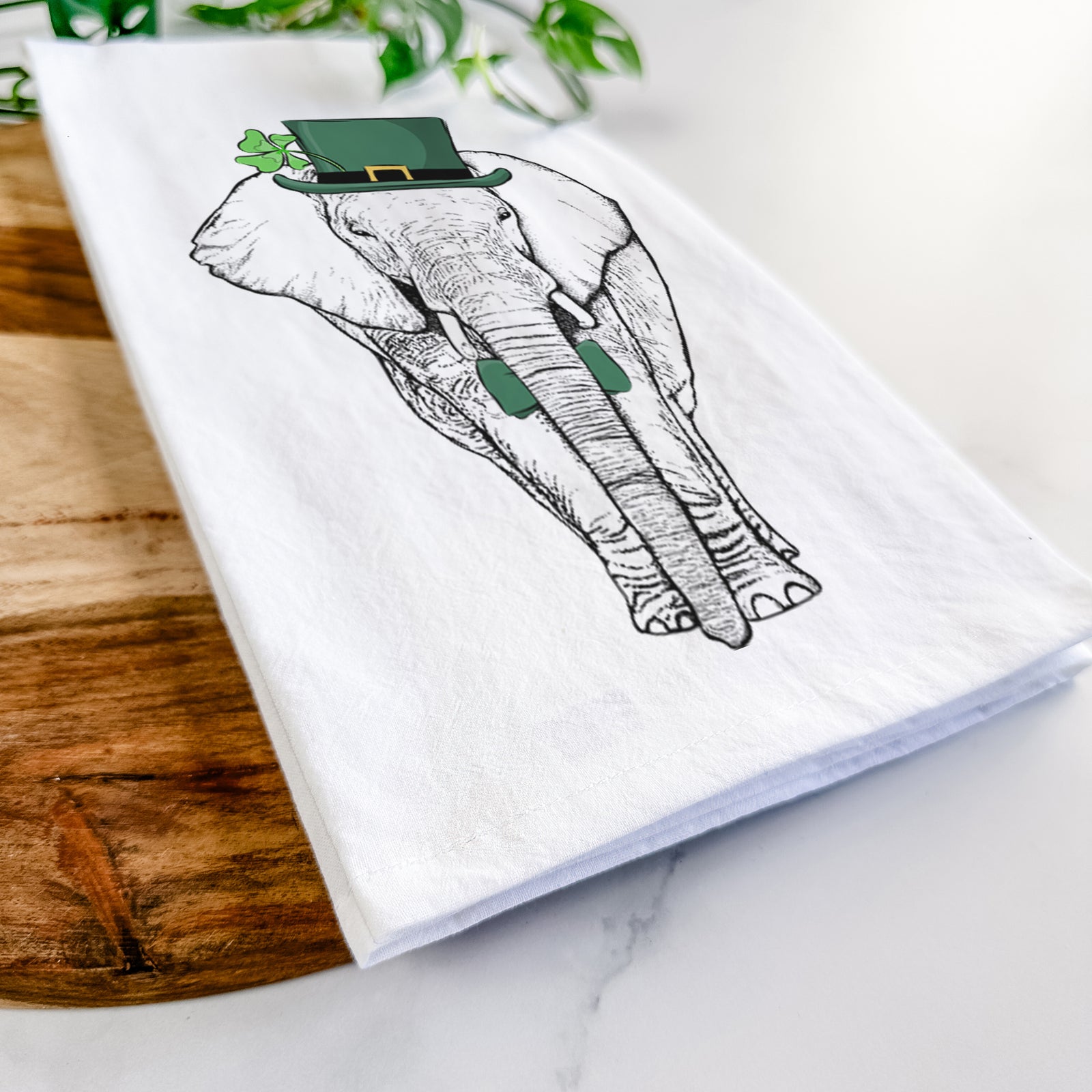 Hand-drawn sketch of Ella the Elephant wearing a St. Patrick's Day leprechaun hat and bow tie on a tea towel