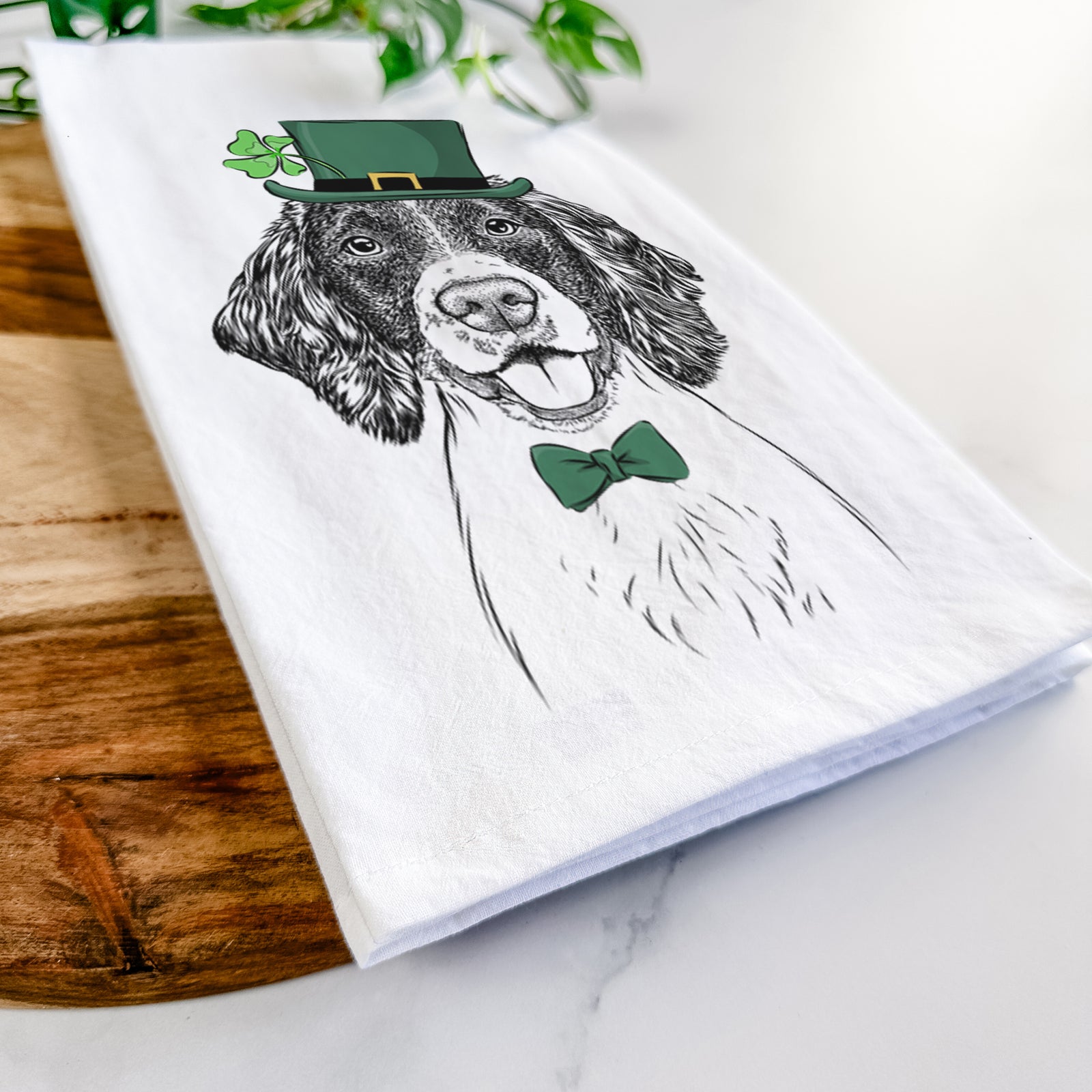 Hand-drawn sketch of Ever the English Springer Spaniel wearing a St. Patrick's Day leprechaun hat and bow tie on a tea towel