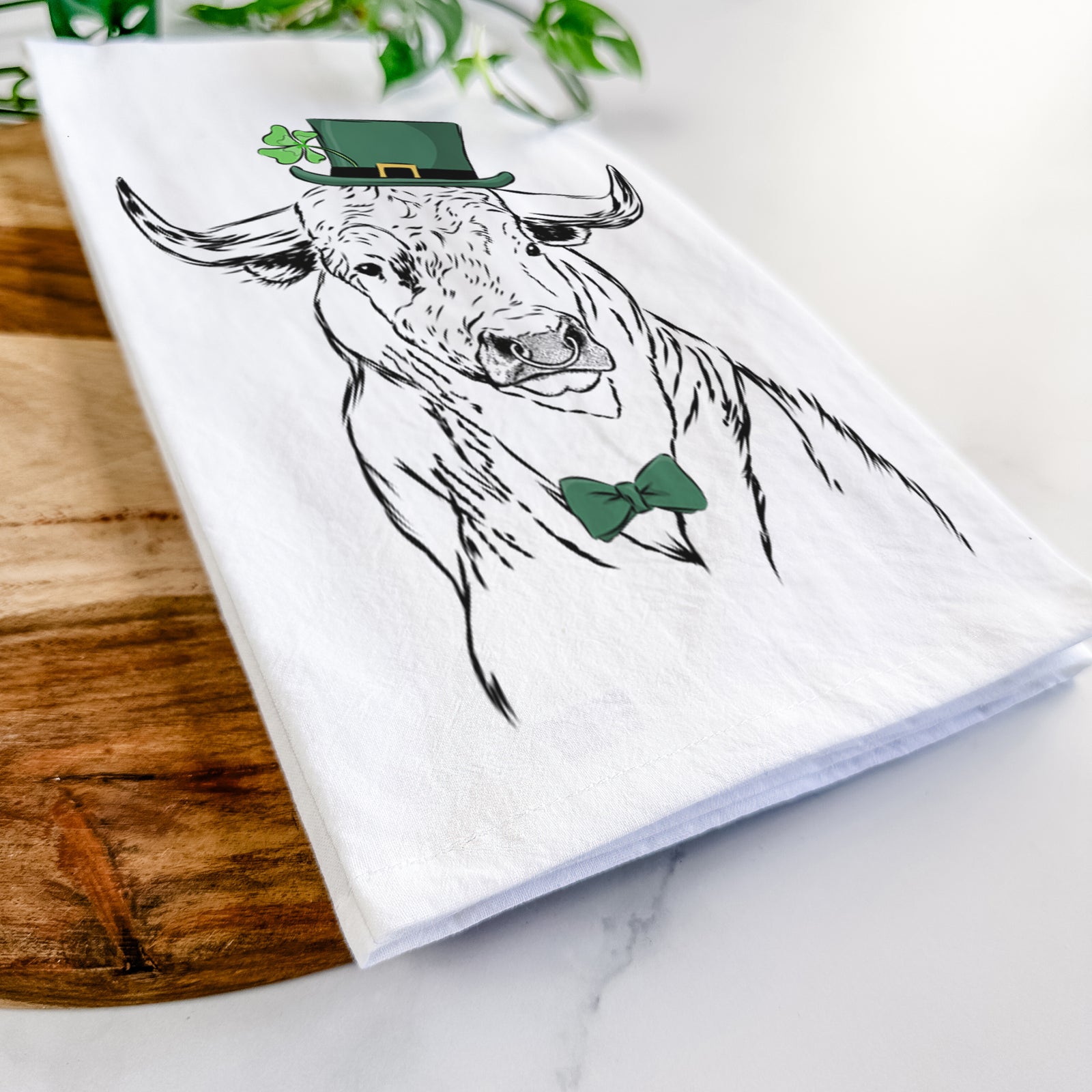 Hand-drawn sketch of Ferdinand the Bull wearing a St. Patrick's Day leprechaun hat and bow tie on a tea towel