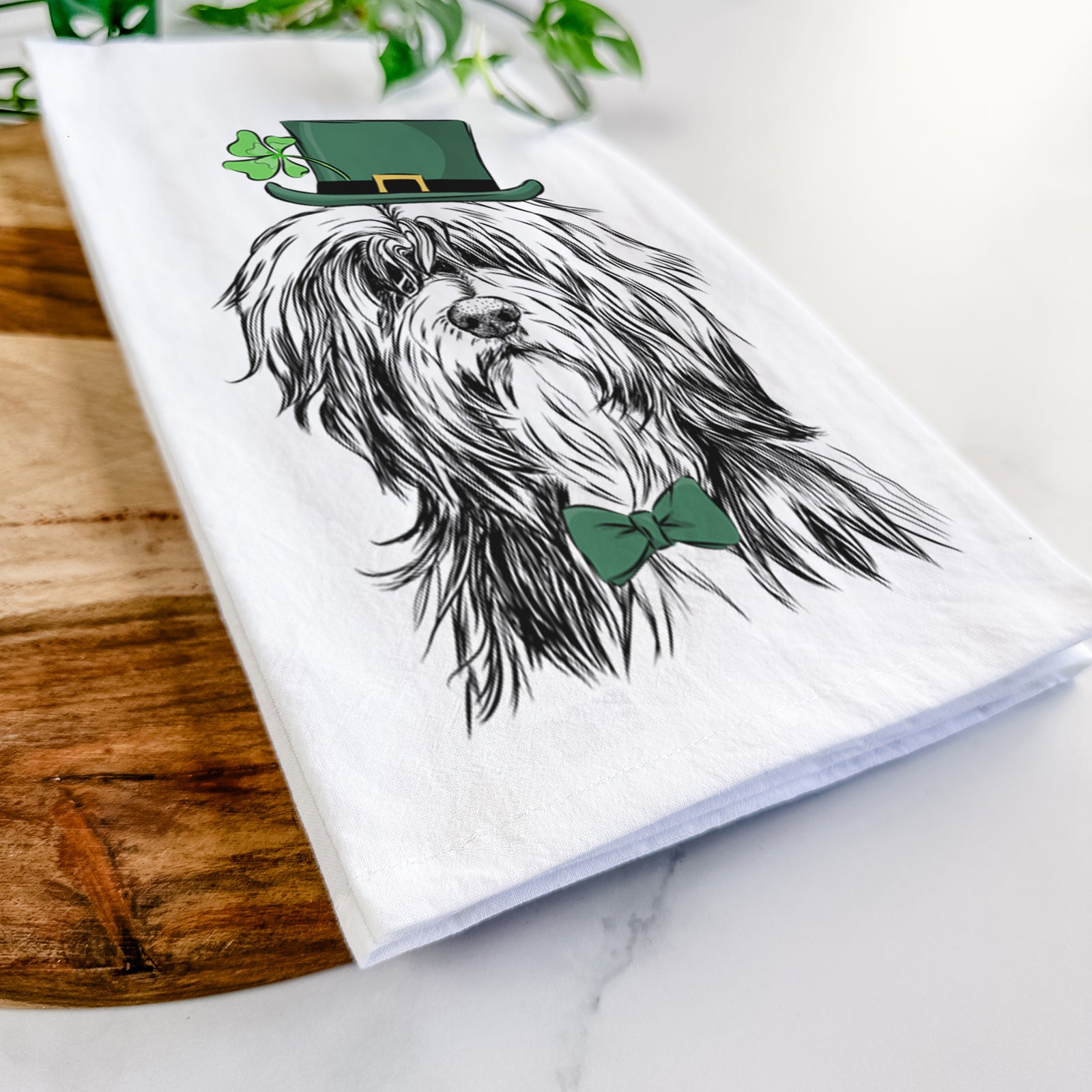 Hand-drawn sketch of Fiji the Polish Lowland Sheepdog wearing a St. Patrick's Day leprechaun hat and bow tie on a tea towel