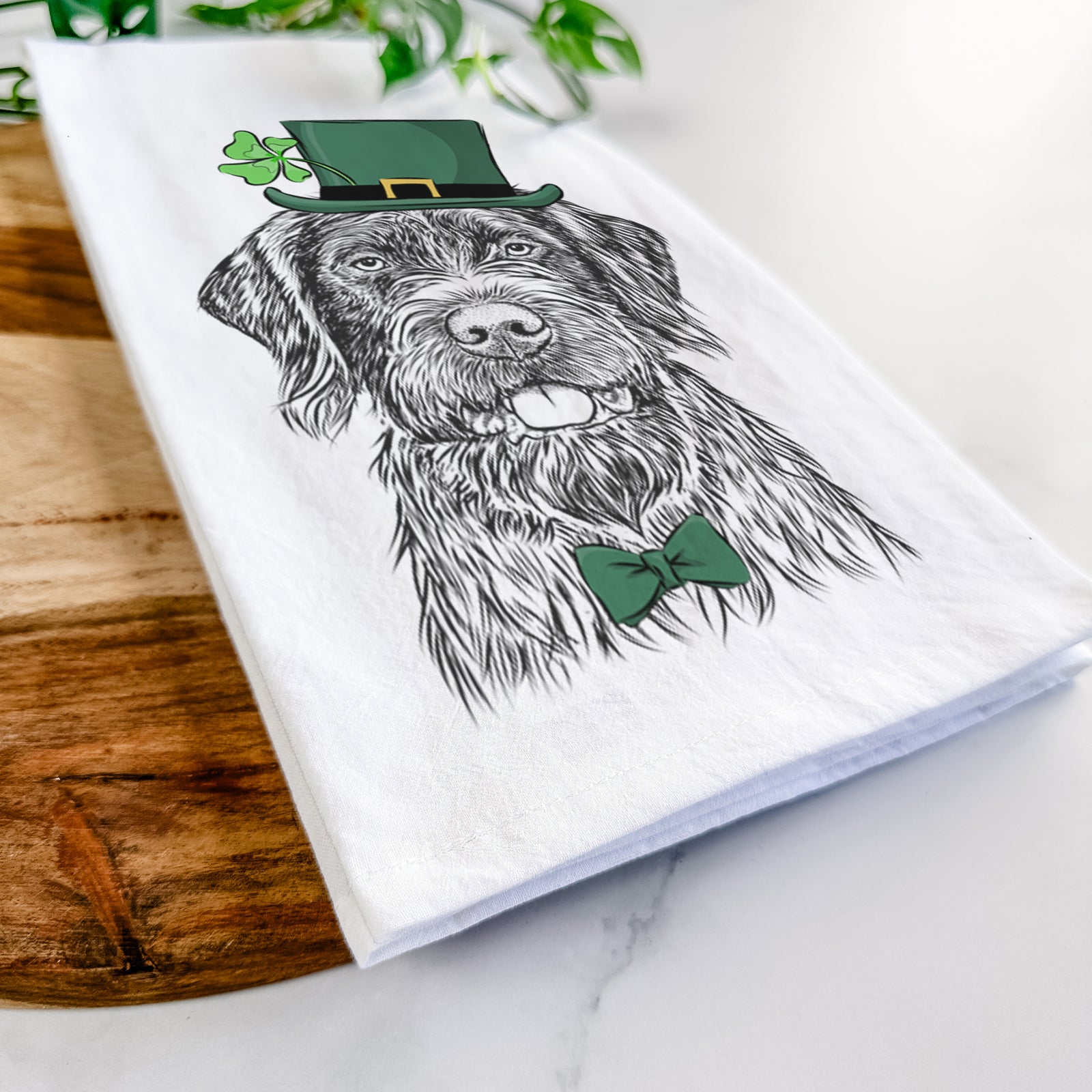 Hand-drawn sketch of Fletcher the Wirehaired Pointing Griffon wearing a St. Patrick's Day leprechaun hat and bow tie on a tea towel