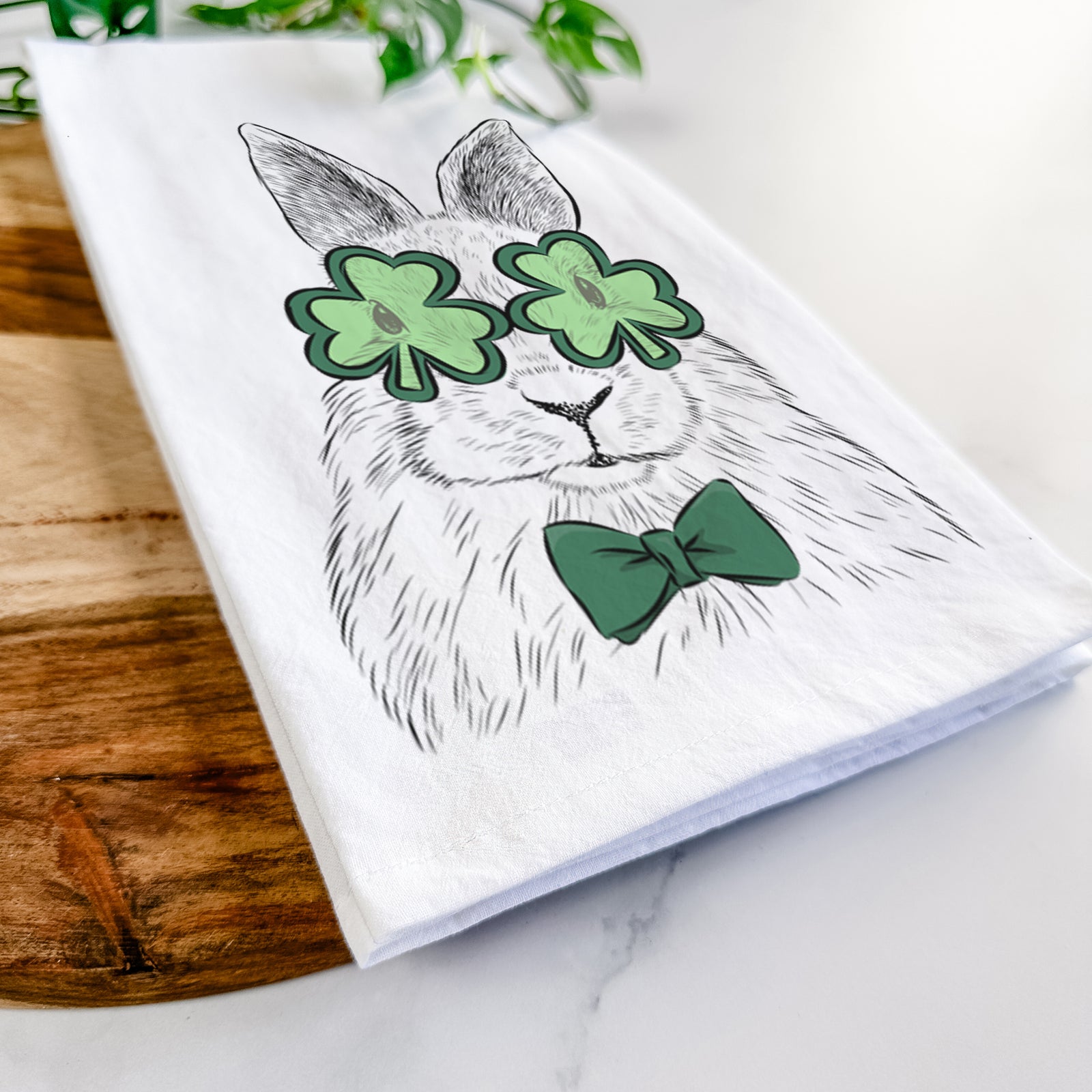 Hand-drawn sketch of Flower the Rex Rabbit wearing a St. Patrick's Day leprechaun hat and bow tie on a tea towel
