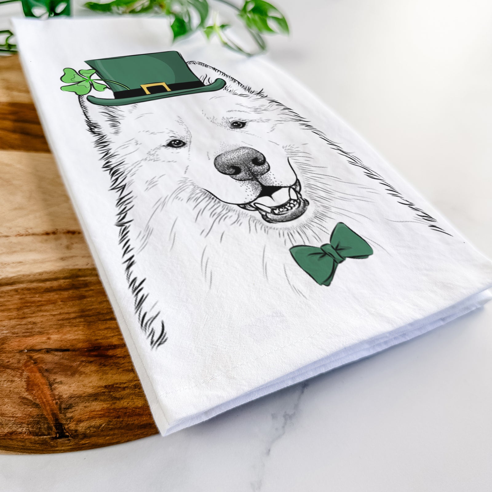 Hand-drawn sketch of Foster the Samoyed wearing a St. Patrick's Day leprechaun hat and bow tie on a tea towel