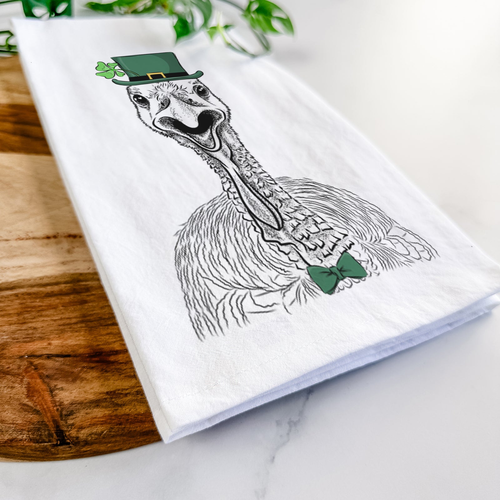 Hand-drawn sketch of Gobble the Turkey wearing a St. Patrick's Day leprechaun hat and bow tie on a tea towel
