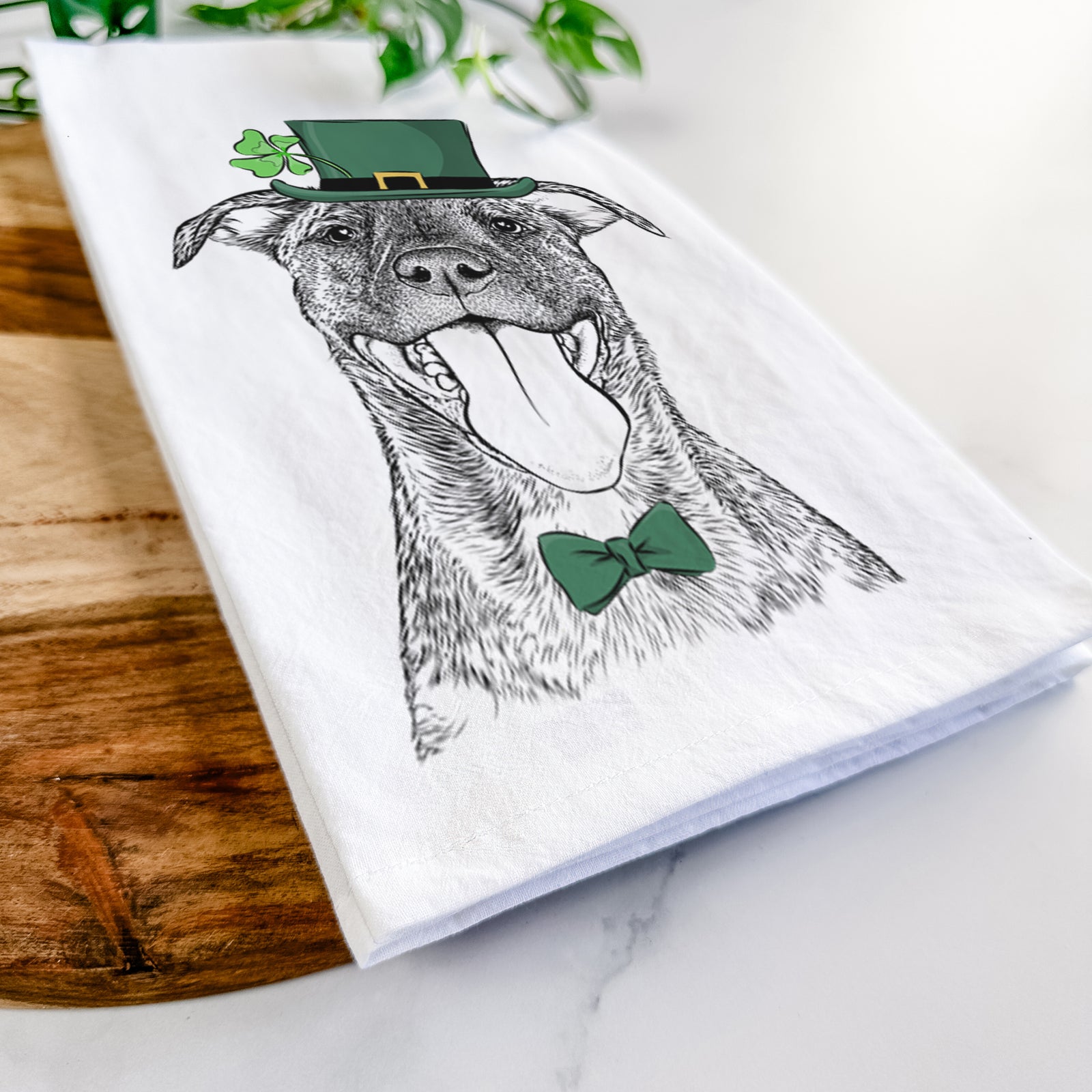 Hand-drawn sketch of Harley the Pitbull Mix wearing a St. Patrick's Day leprechaun hat and bow tie on a tea towel