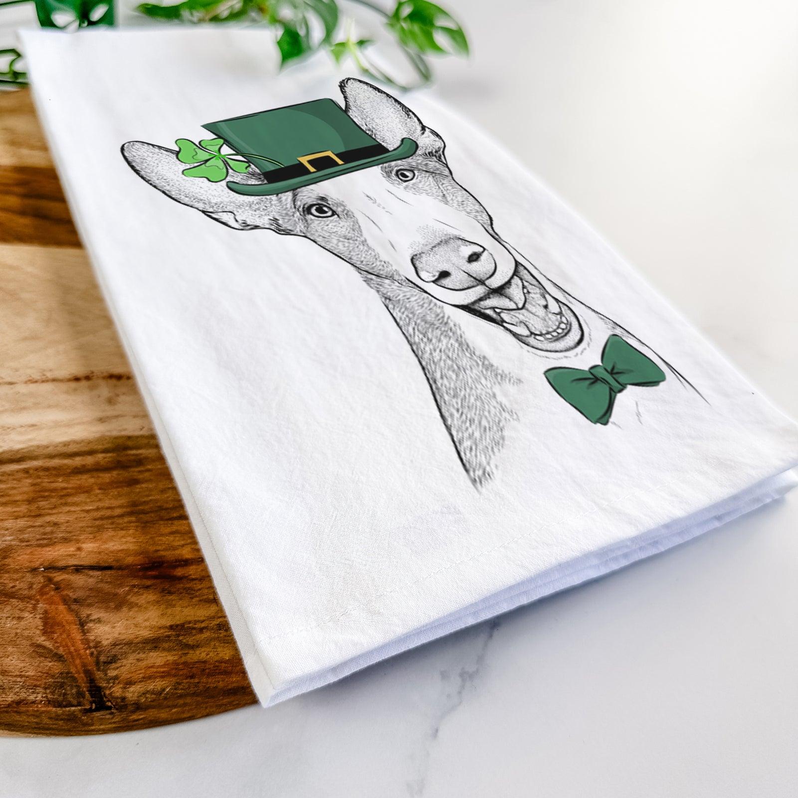 Hand-drawn sketch of Havok the Ibizan Hound wearing a St. Patrick's Day leprechaun hat and bow tie on a tea towel