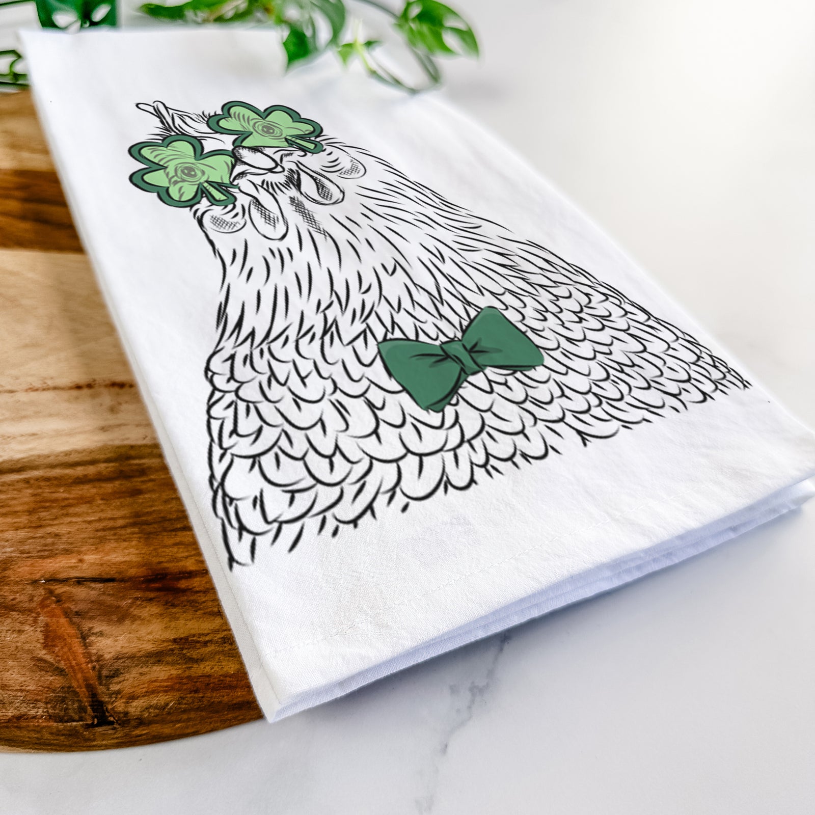 Hand-drawn sketch of Henrietta the Chicken wearing a St. Patrick's Day leprechaun hat and bow tie on a tea towel