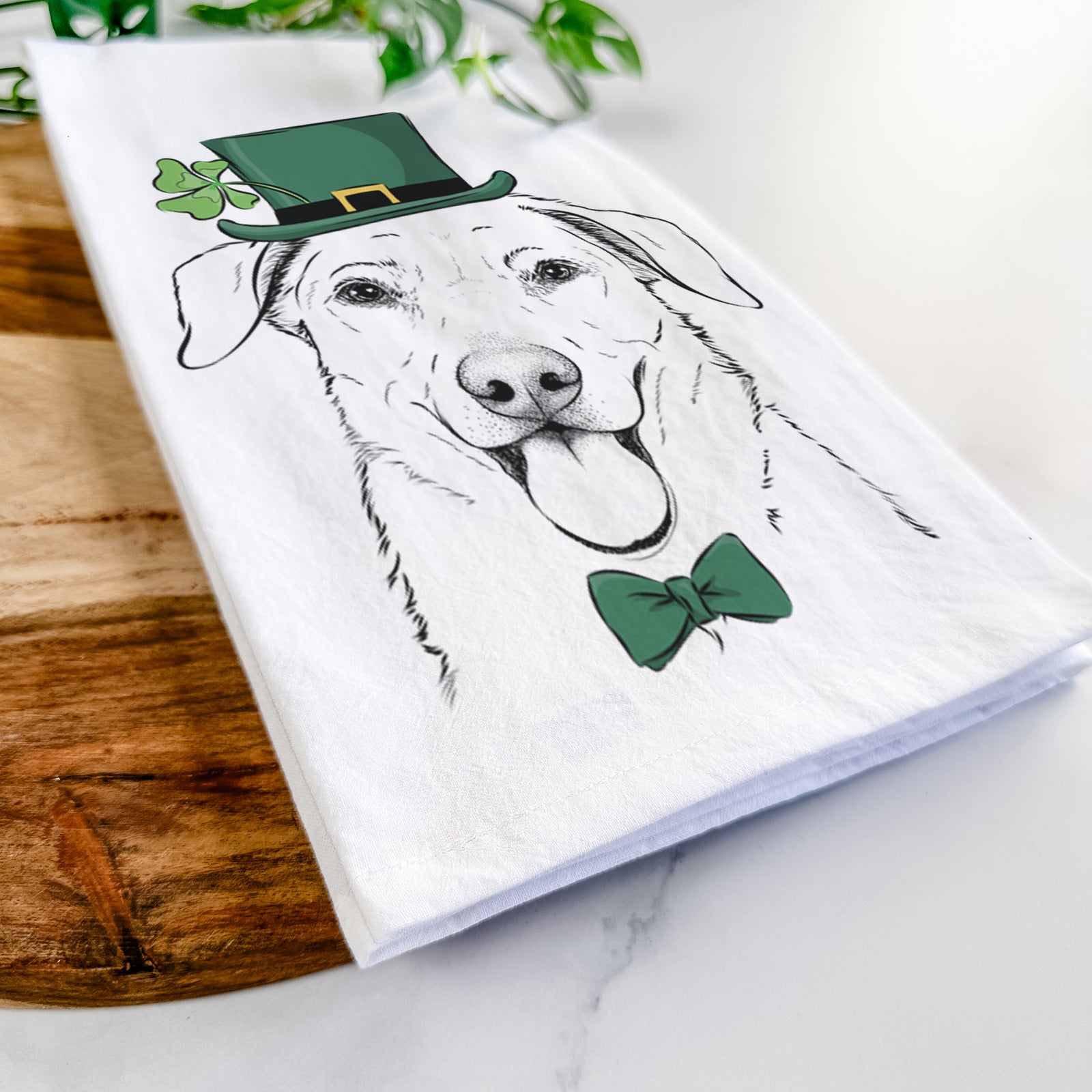 Hand-drawn sketch of Hudson the Shepherd wearing a St. Patrick's Day leprechaun hat and bow tie on a tea towel