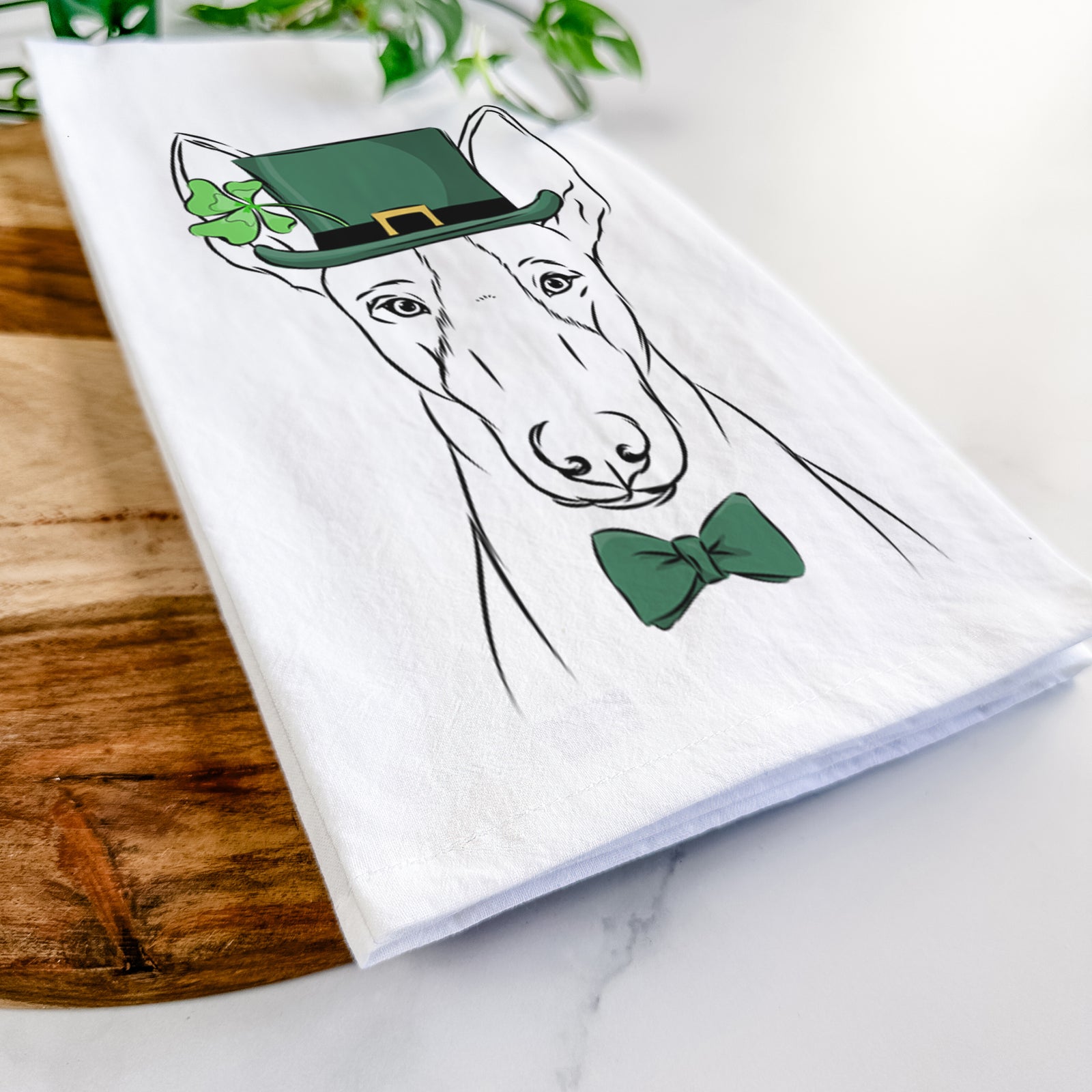 Hand-drawn sketch of Indy the Ibizan Hound wearing a St. Patrick's Day leprechaun hat and bow tie on a tea towel