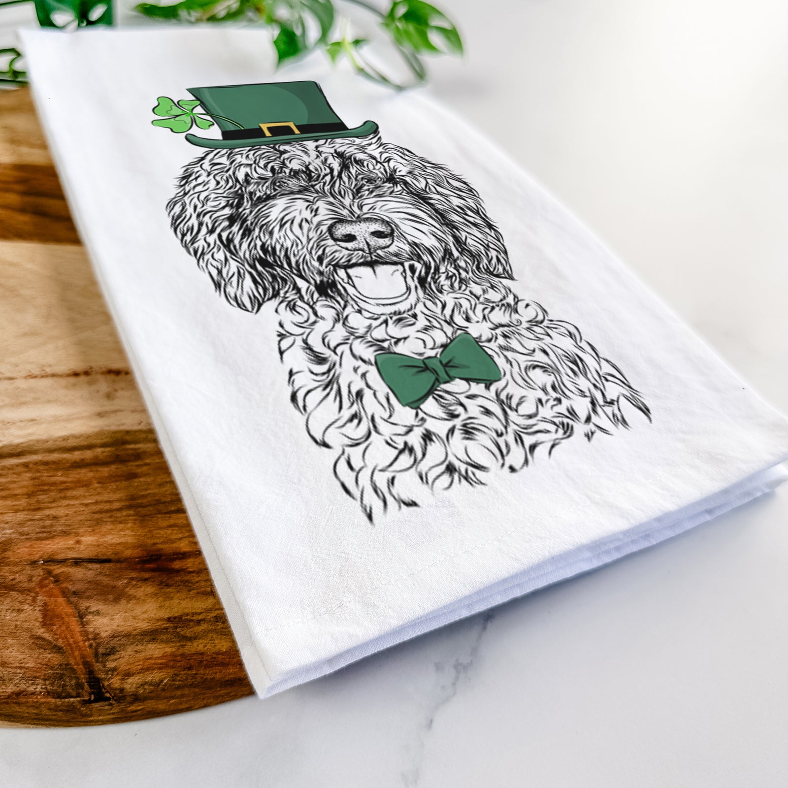 Hand-drawn sketch of Jack the Chocolate Labradoodle wearing a St. Patrick's Day leprechaun hat and bow tie on a tea towel