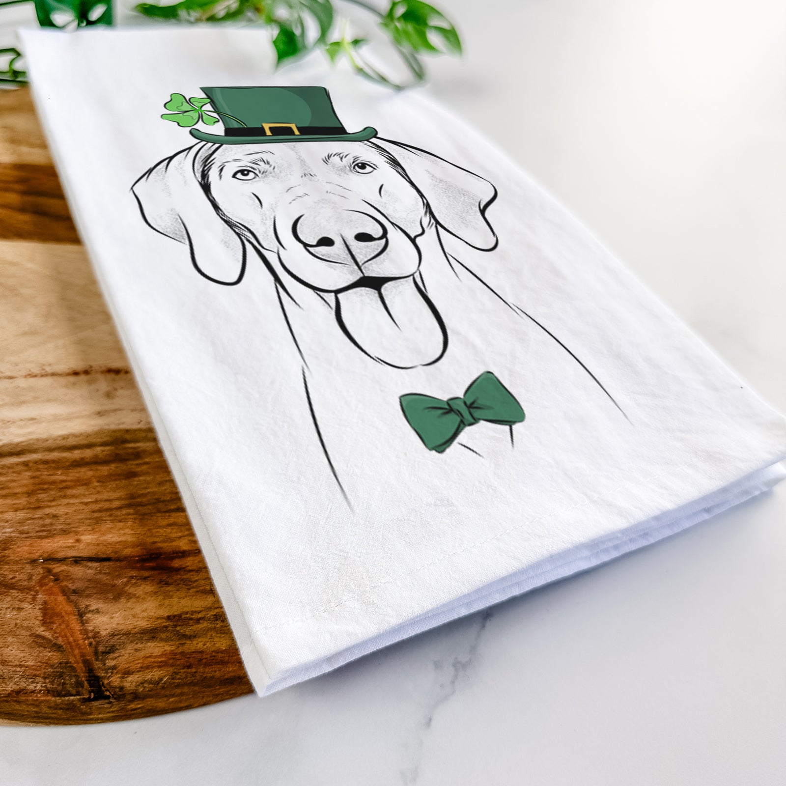 Hand-drawn sketch of Jackson the Weimaraner wearing a St. Patrick's Day leprechaun hat and bow tie on a tea towel