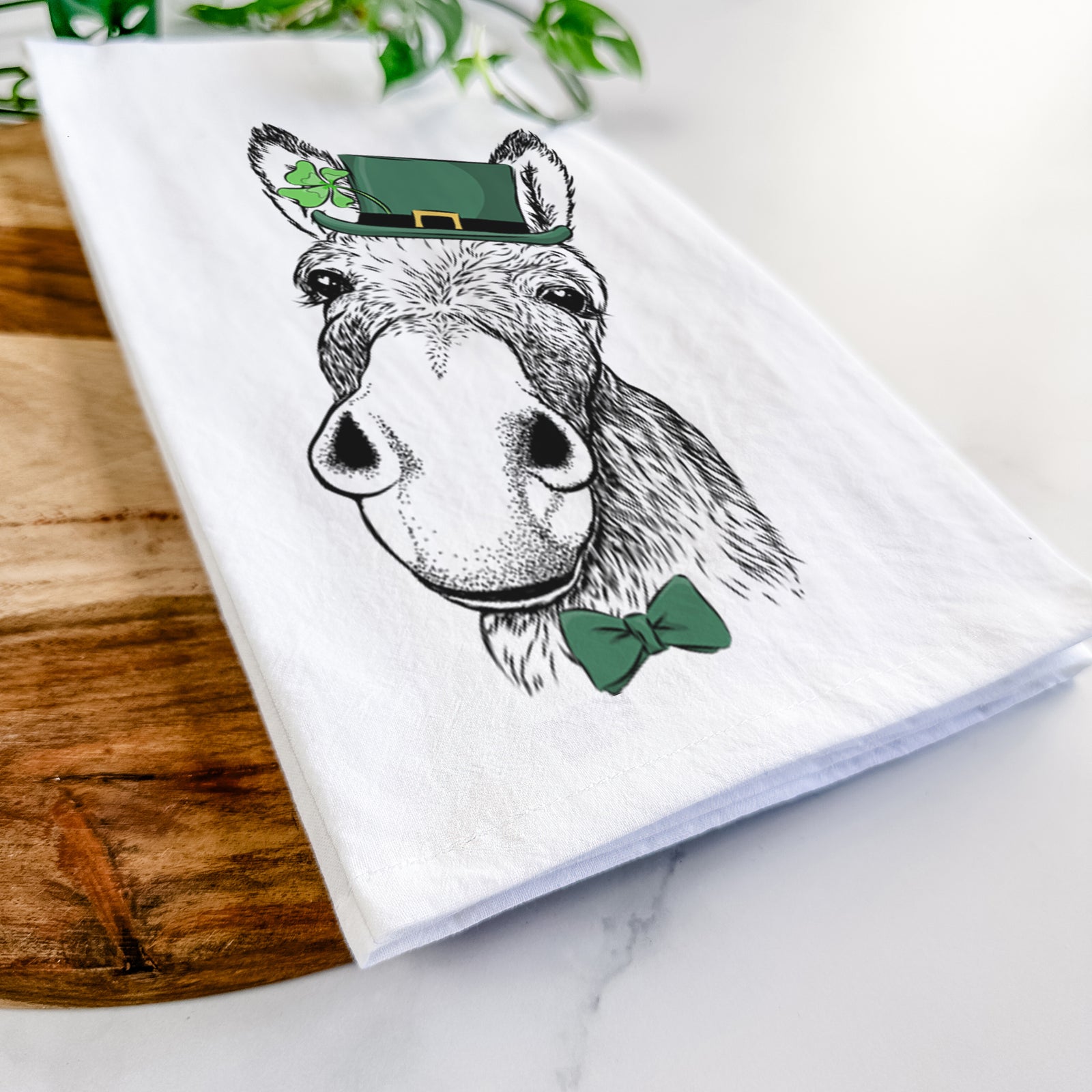 Hand-drawn sketch of Jenny the Donkey wearing a St. Patrick's Day leprechaun hat and bow tie on a tea towel