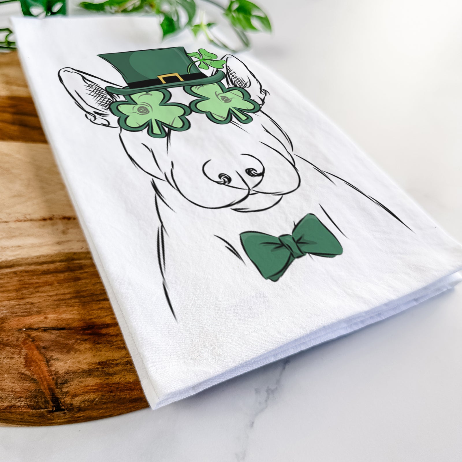 Hand-drawn sketch of Jett the Bull Terrier wearing a St. Patrick's Day leprechaun hat and bow tie on a tea towel
