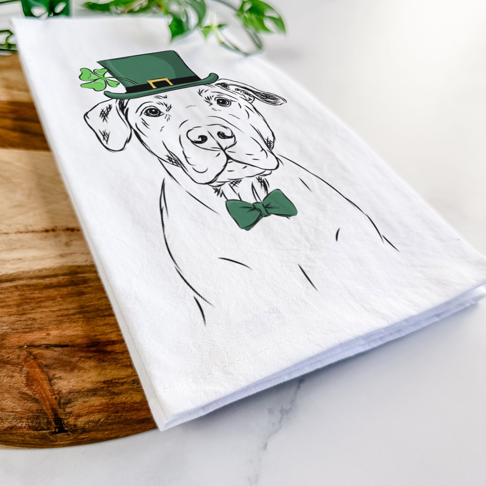 Hand-drawn sketch of Kadin the Pitbull wearing a St. Patrick's Day leprechaun hat and bow tie on a tea towel