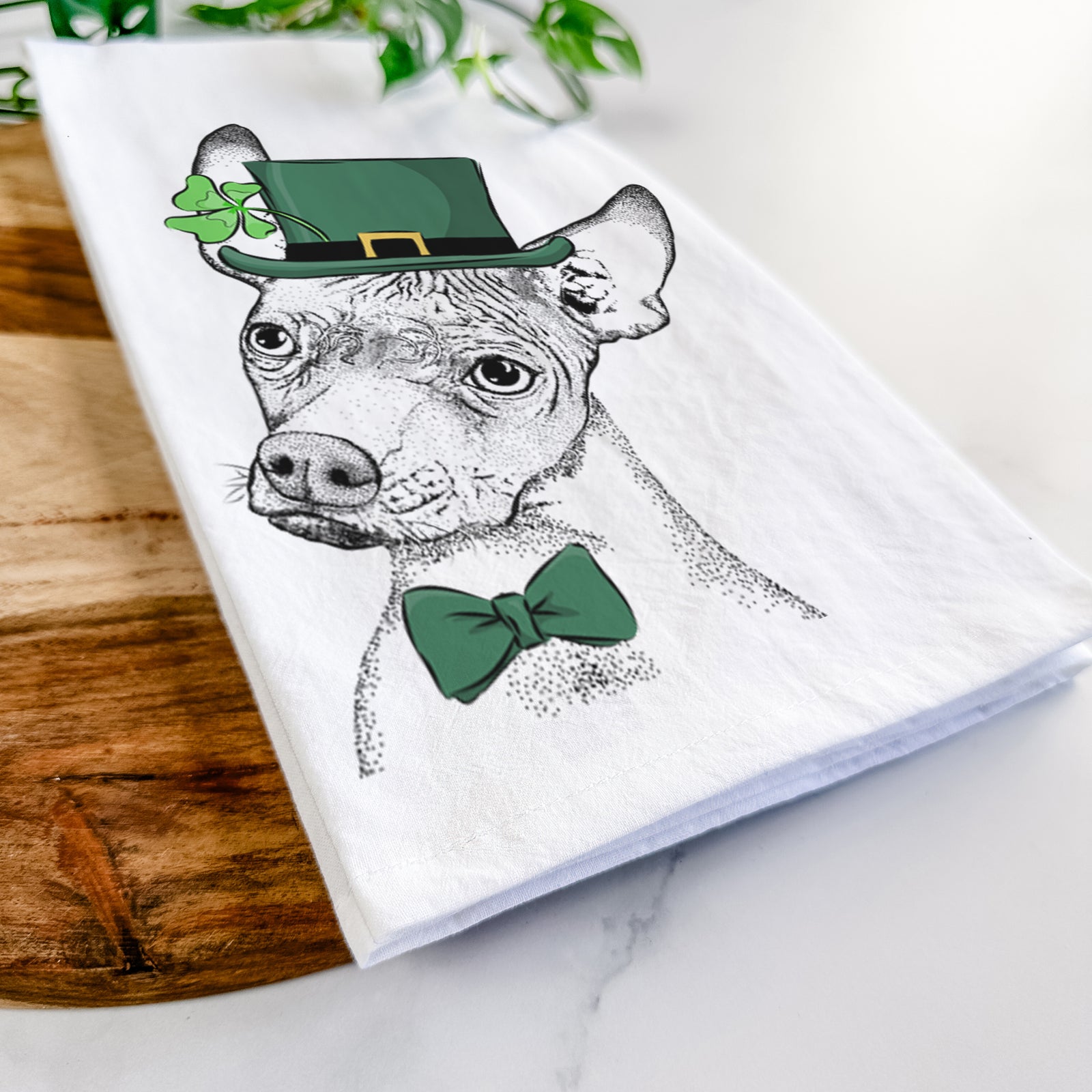 Hand-drawn sketch of Kahlo the Xoloitzcuintli wearing a St. Patrick's Day leprechaun hat and bow tie on a tea towel