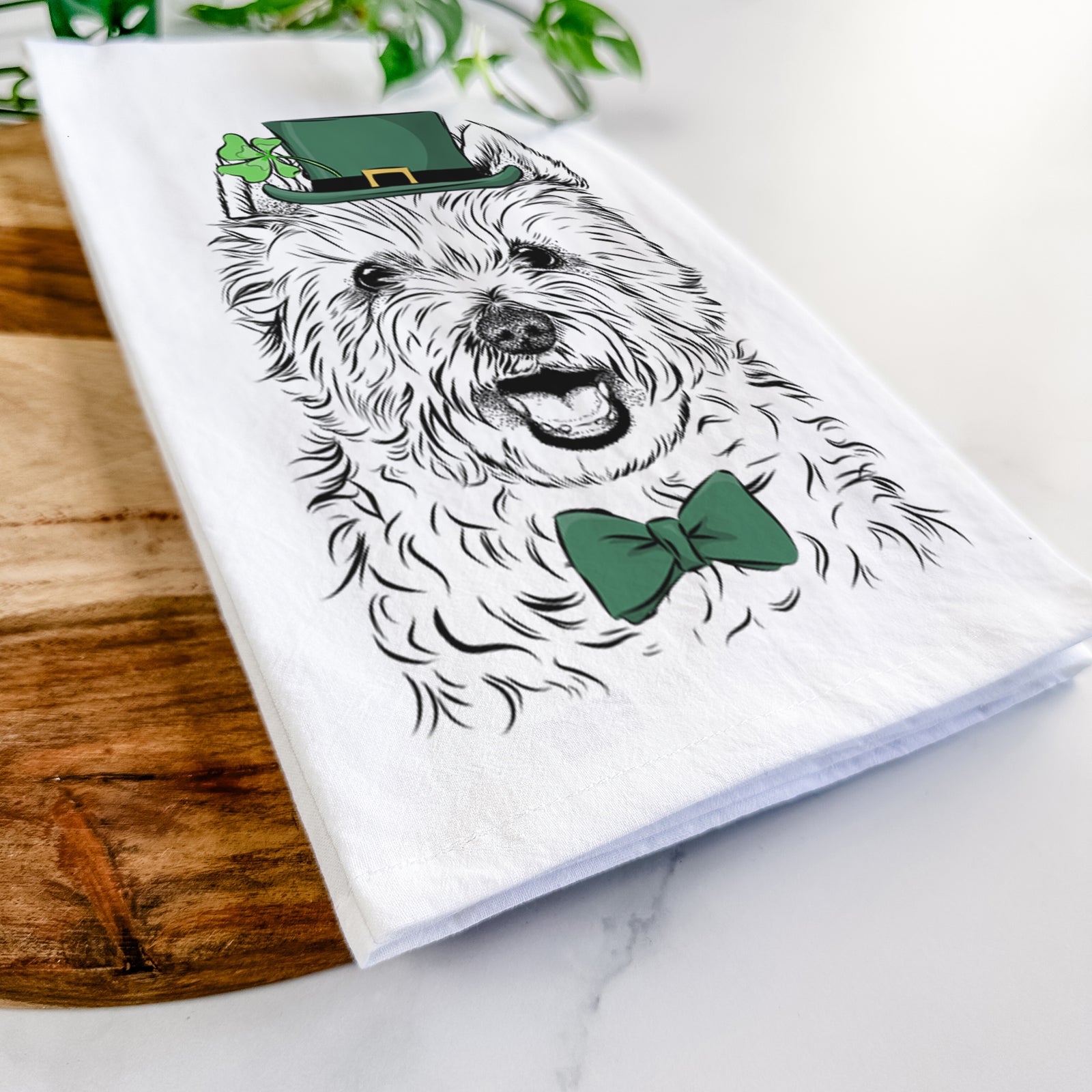 Hand-drawn sketch of Kami the West Highland Terrier wearing a St. Patrick's Day leprechaun hat and bow tie on a tea towel