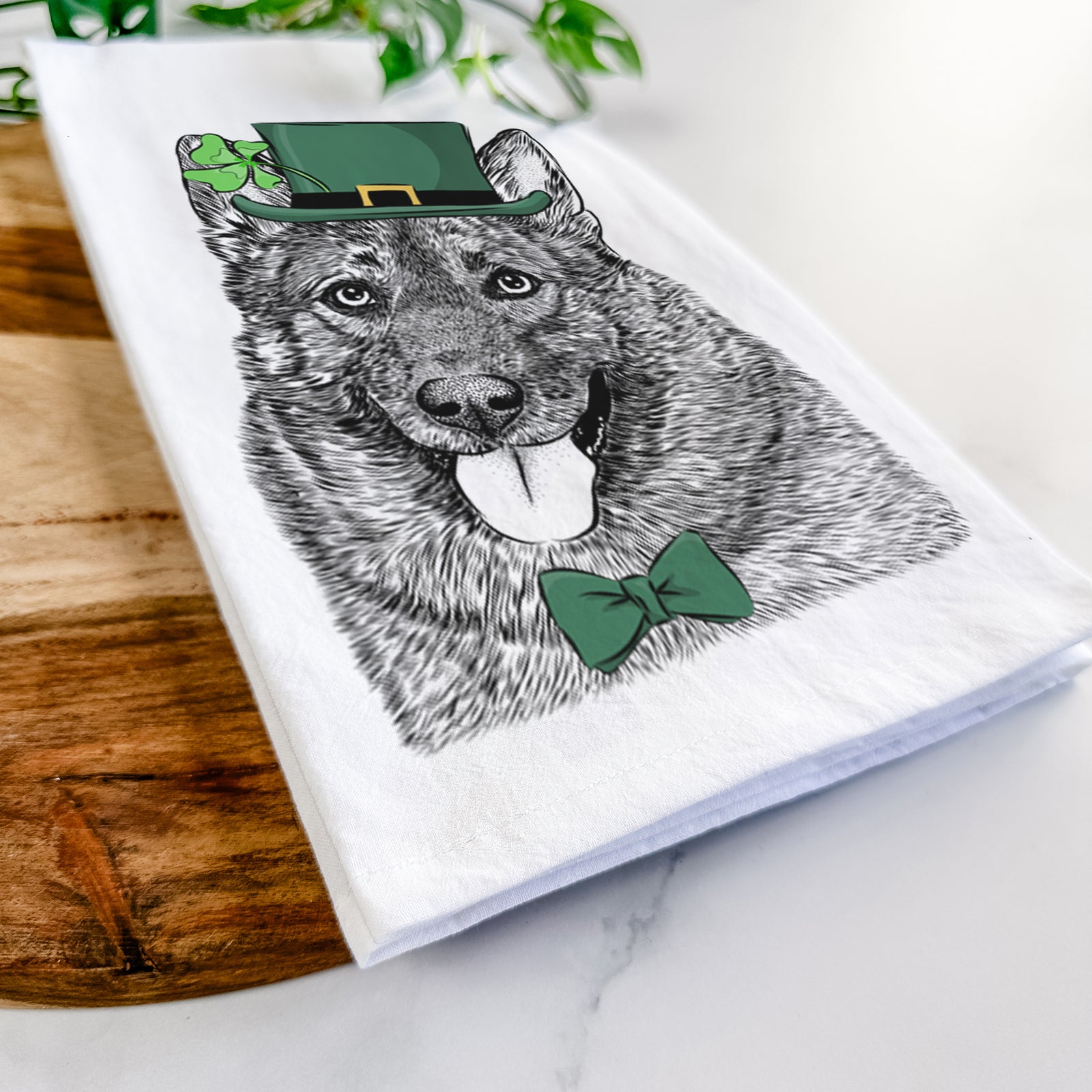 Hand-drawn sketch of Kasia the Norwegian Elkhound wearing a St. Patrick's Day leprechaun hat and bow tie on a tea towel